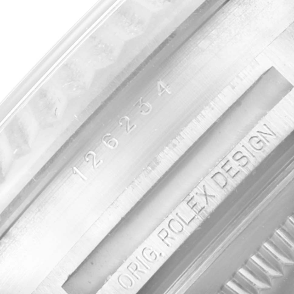 The image shows a close-up of the serial number and "ORIG. ROLEX DESIGN" engraving on the side of the Rolex Datejust 126234 Men
s Stainless Steel Silver Dial 126234 Men
s Stainless Steel Silver Dial watch case.