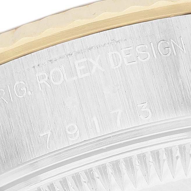 The image shows a close-up of the side of a Rolex Datejust 79173 Women's Stainless Steel Black Dial watch, focusing on the engraved serial number and bezel edge.
