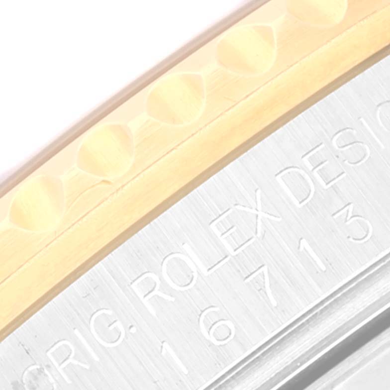 The image shows a close-up of the edge and engraved text on the case of a Rolex GMT-Master 16713 Men's Steel and Gold (two tone) Brown Dial 16713 Men's Steel and Gold (two tone) Brown Dial watch.