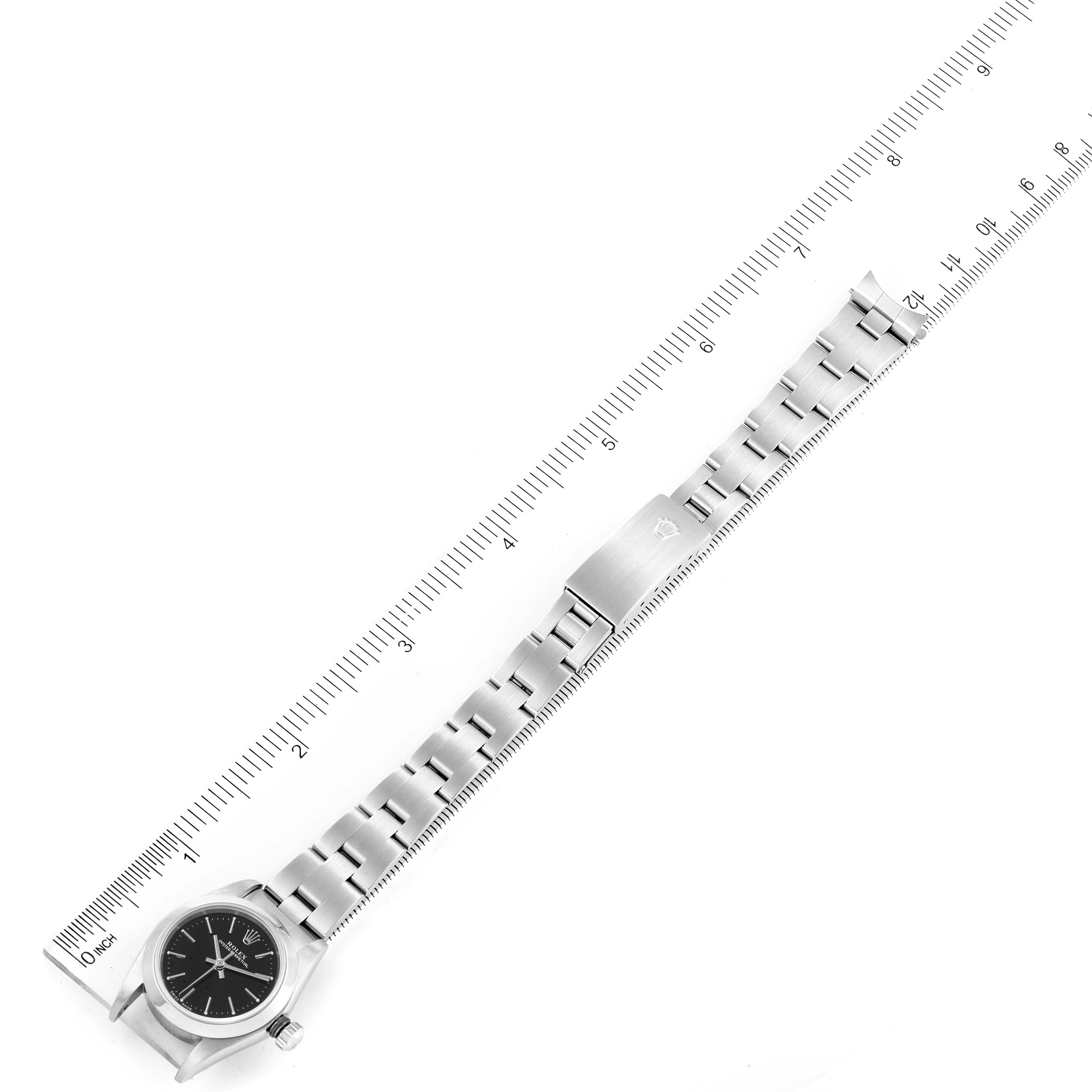 The image shows a top-down view of a Rolex Oyster Perpetual 76080 Women's Stainless Steel Black Dial 76080 Women's Stainless Steel Black Dial watch with its band laid flat next to a ruler.