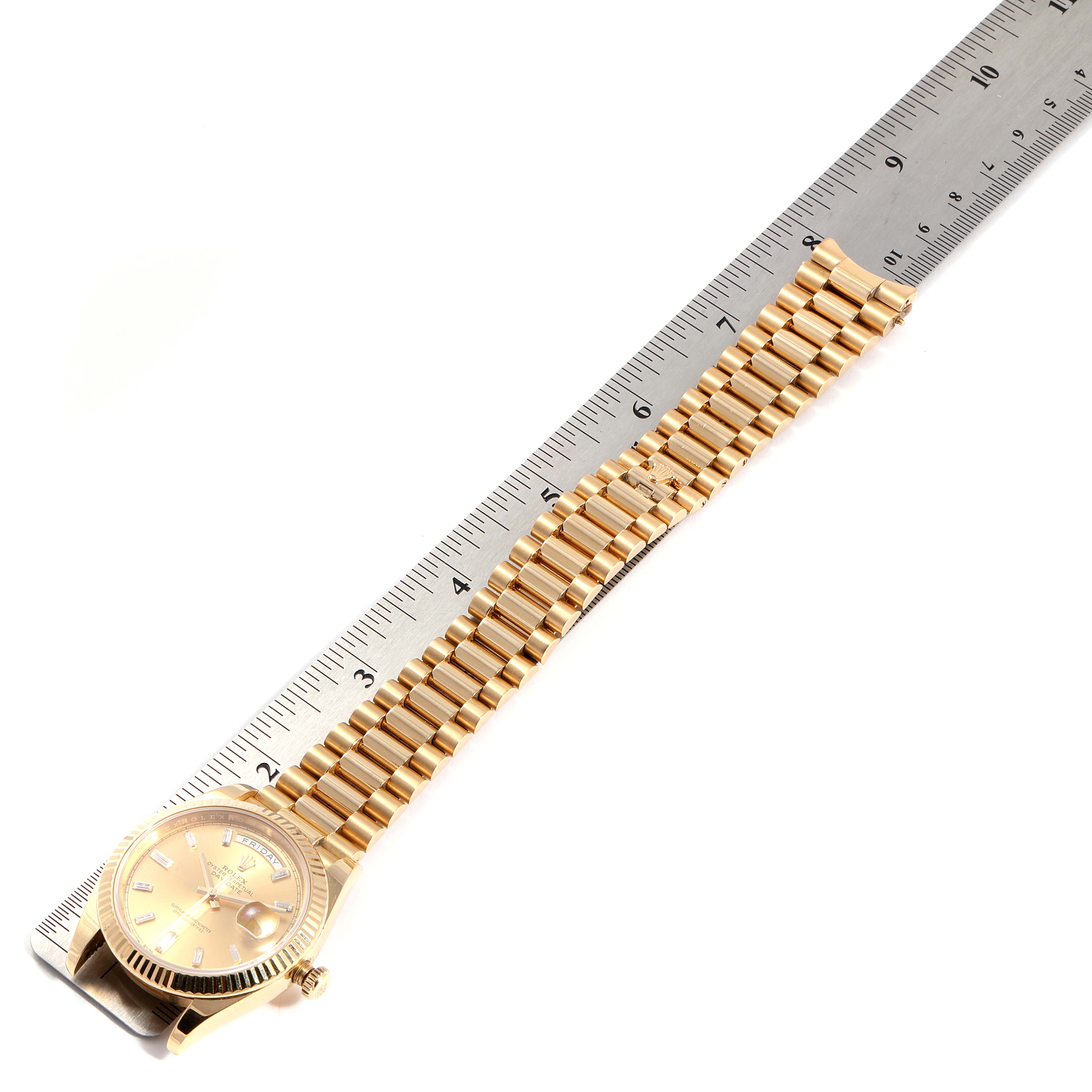 This image shows the Rolex President 228238 Men's Yellow Gold Champagne Dial 228238 Men's Yellow Gold Champagne Dial watch model laid flat next to a ruler, highlighting the case, dial, crown, and bracelet.