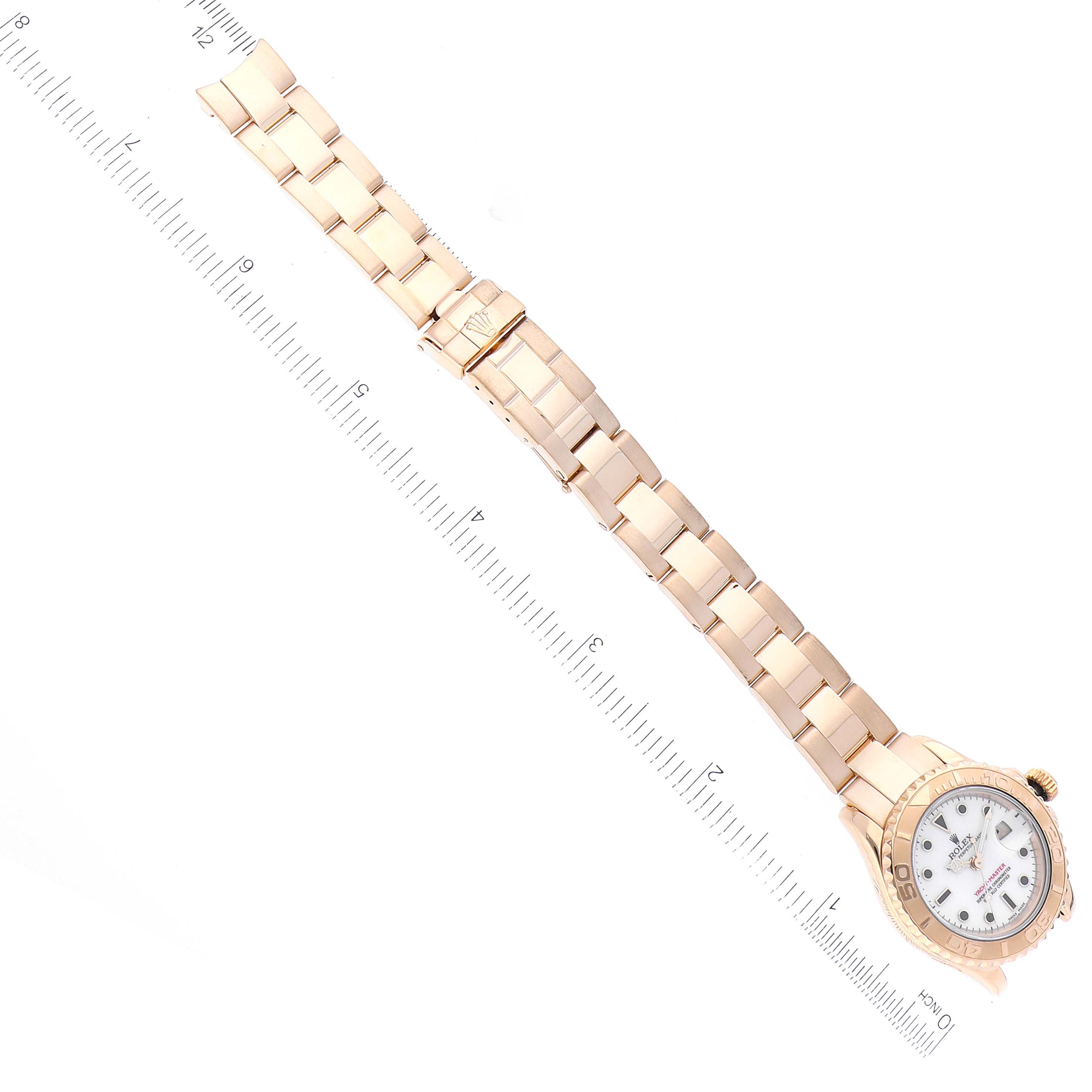 The image shows a full, extended view of a Rolex Yacht-Master 69628 Women's Yellow Gold White Dial 69628 Women's Yellow Gold White Dial watch laid flat next to a ruler.