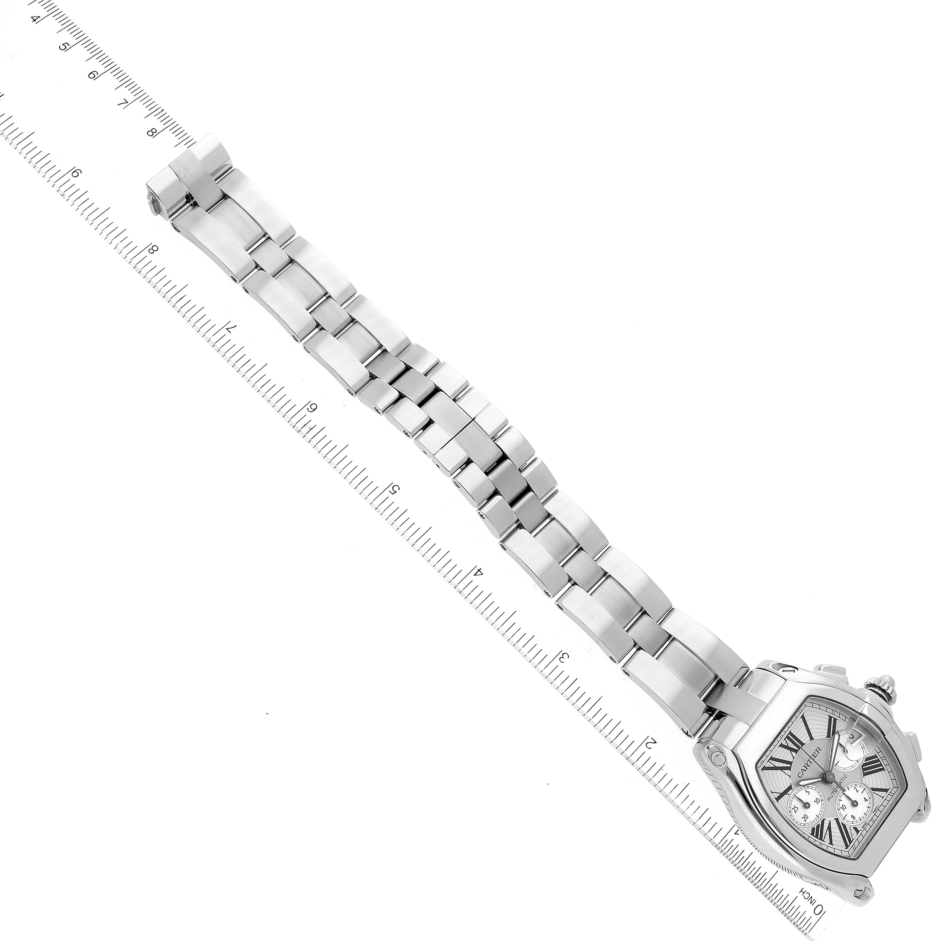 This image shows an aerial view of a Cartier Roadster W62019X6 Men's Stainless Steel Silver Dial W62019X6 Men's Stainless Steel Silver Dial watch with its full metal bracelet and a measuring ruler beside it.