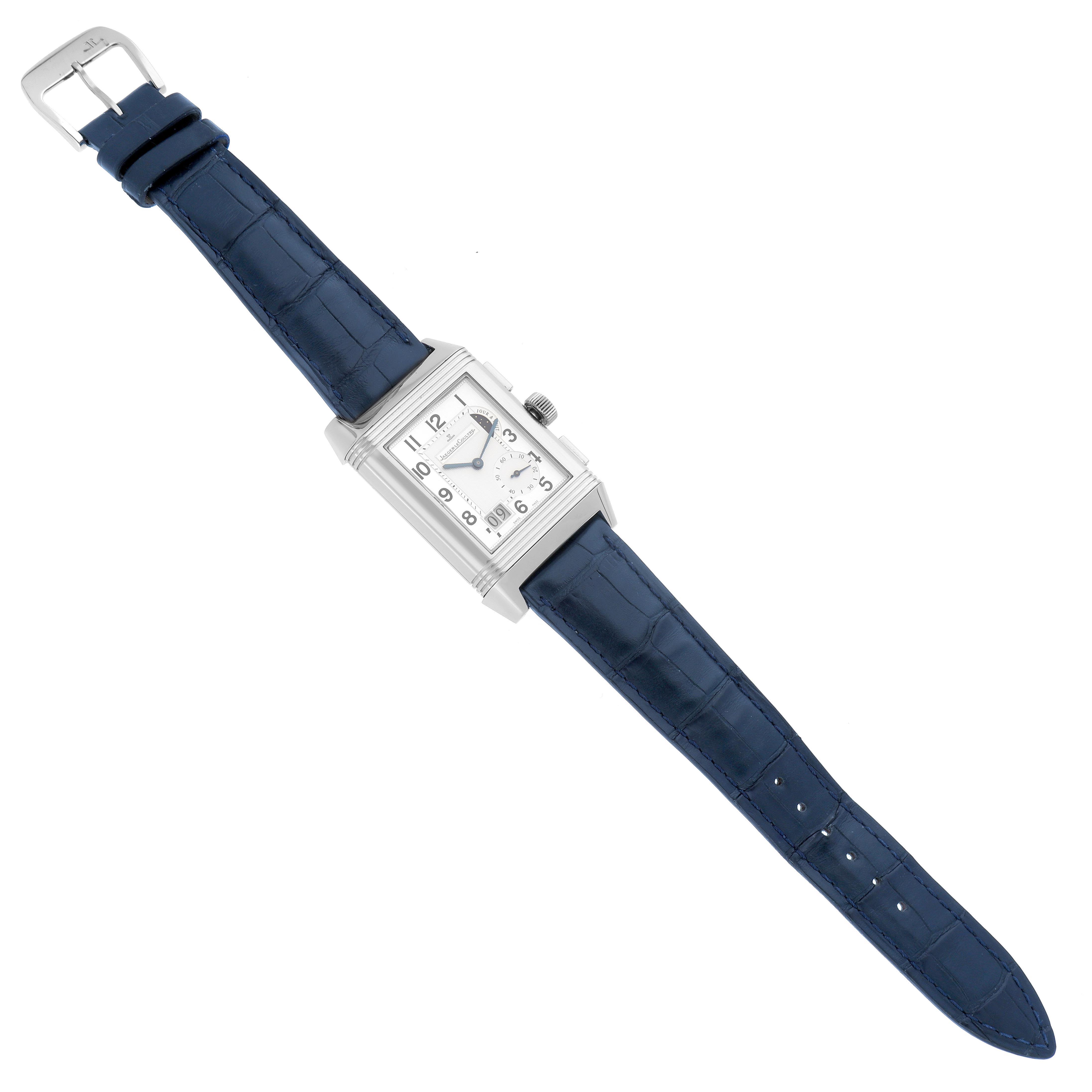 The Jaeger-LeCoultre Reverso watch is shown flat with a blue leather strap and a rectangular face, set at a top-down angle.