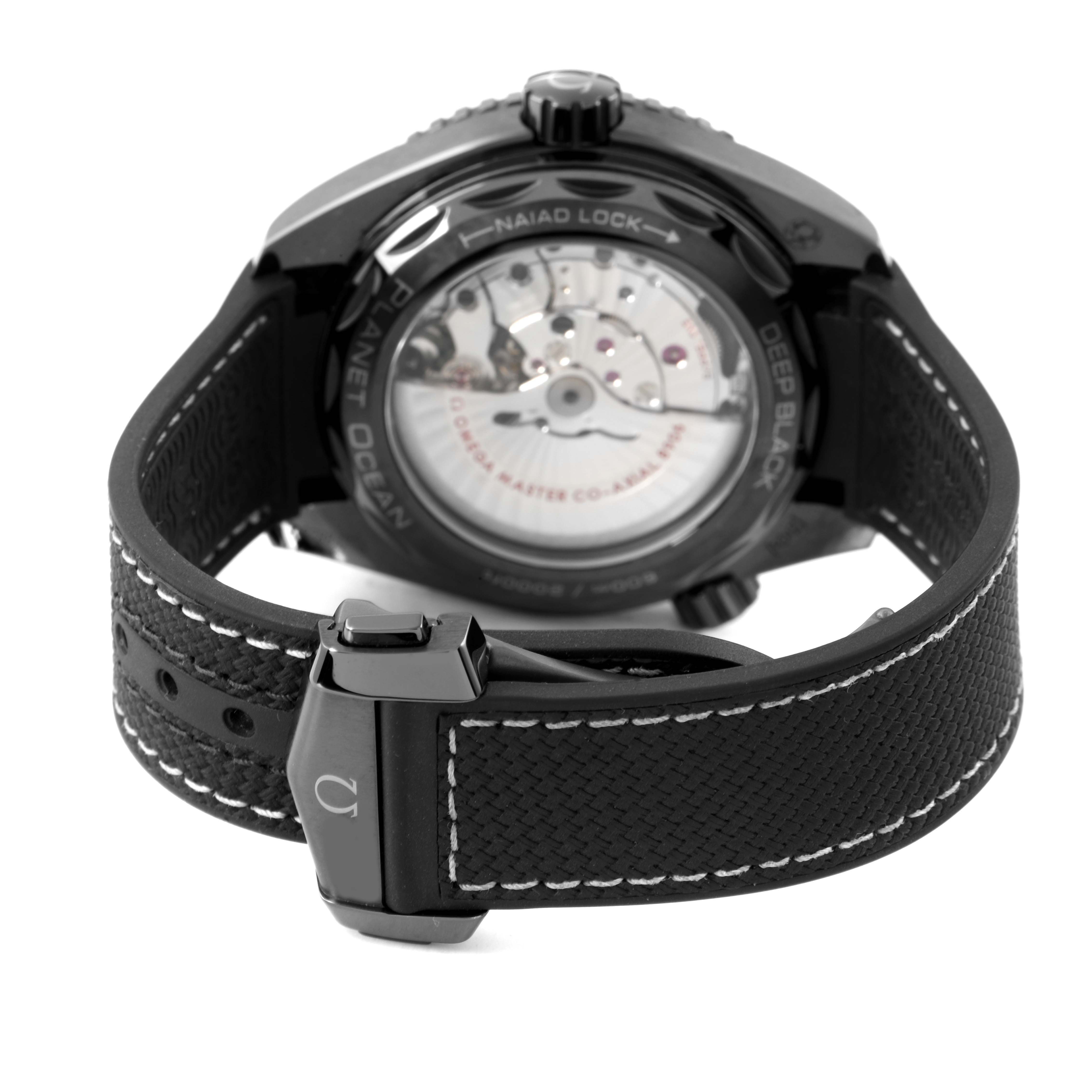 The image shows the back view of an Omega Planet Ocean 215.92.46.22.01.001 Men's Ceramic Black Dial watch, highlighting the transparent case back and black strap with stitching.