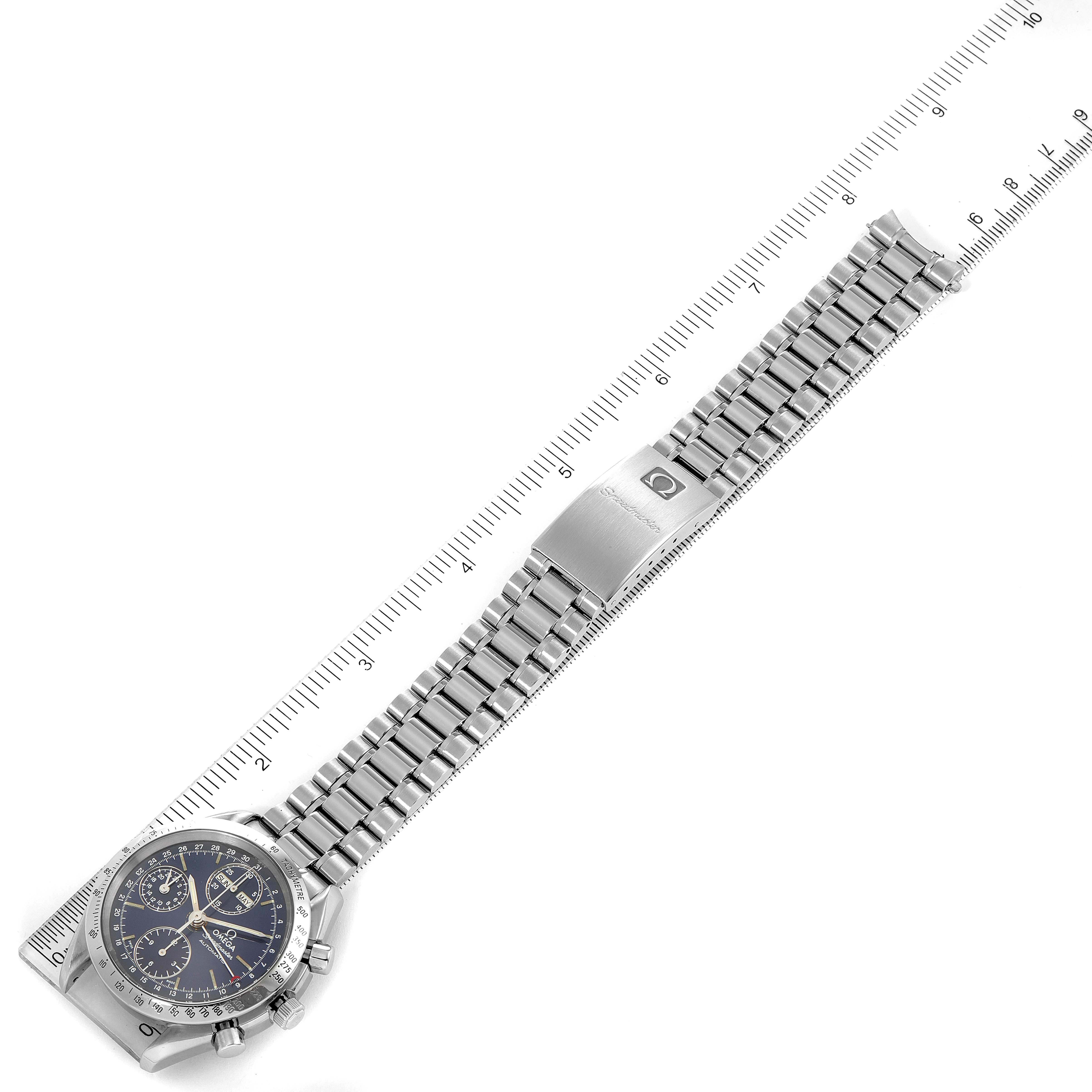 The image shows an Omega Speedmaster 3521.80.00 Men
s Stainless Steel Blue Dial 3521.80.00 Men
s Stainless Steel Blue Dial watch viewed from above, displaying the dial, bracelet, and clasp alongside a ruler for scale.
