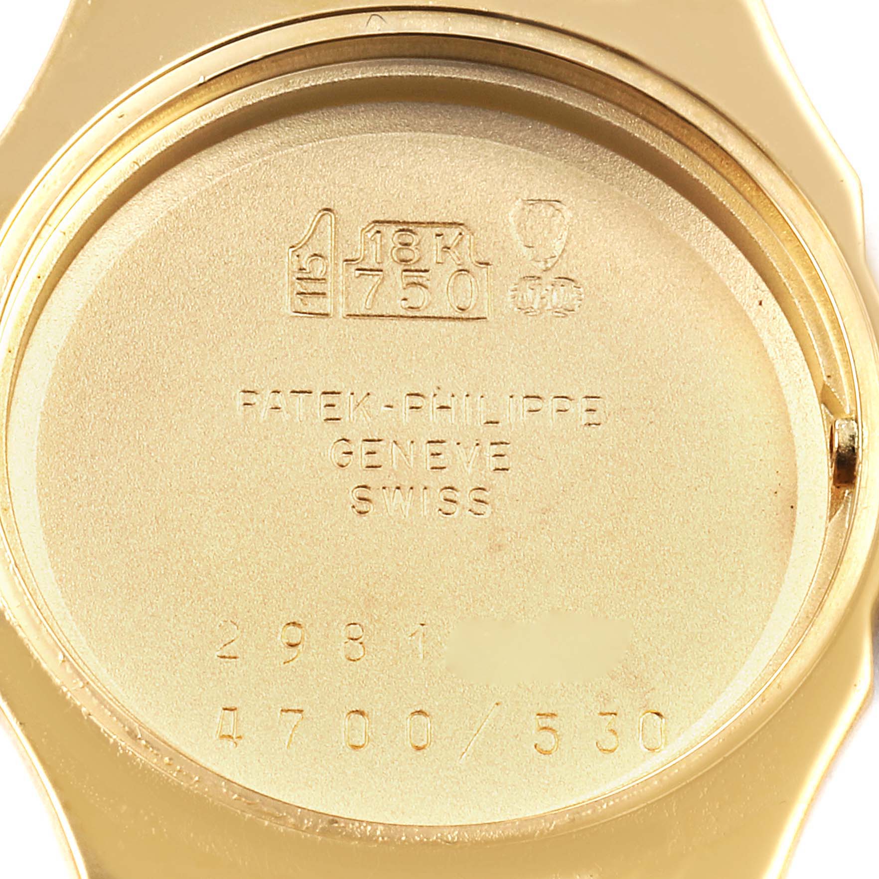 The image shows the case back of a Patek Philippe Nautilus 4700/530 Women's Yellow Gold Beige Dial 4700/530 Women's Yellow Gold Beige Dial watch in gold, featuring hallmark stamps and inscriptions.