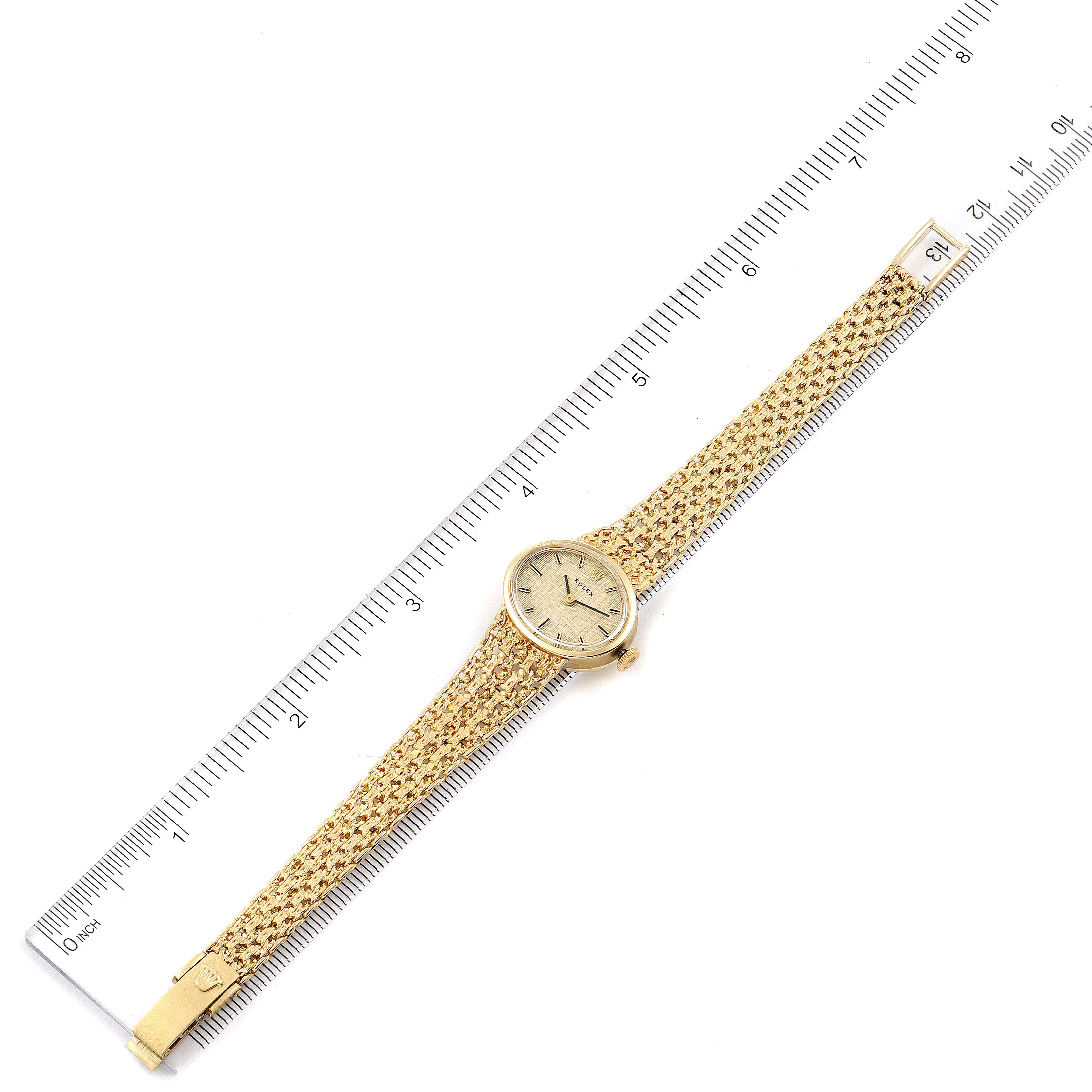 The image shows a top-down view of the Rolex Cocktail  Women's Yellow Gold Champagne Dial  Women's Yellow Gold Champagne Dial model watch, displaying its face and full bracelet alongside a ruler for scale.