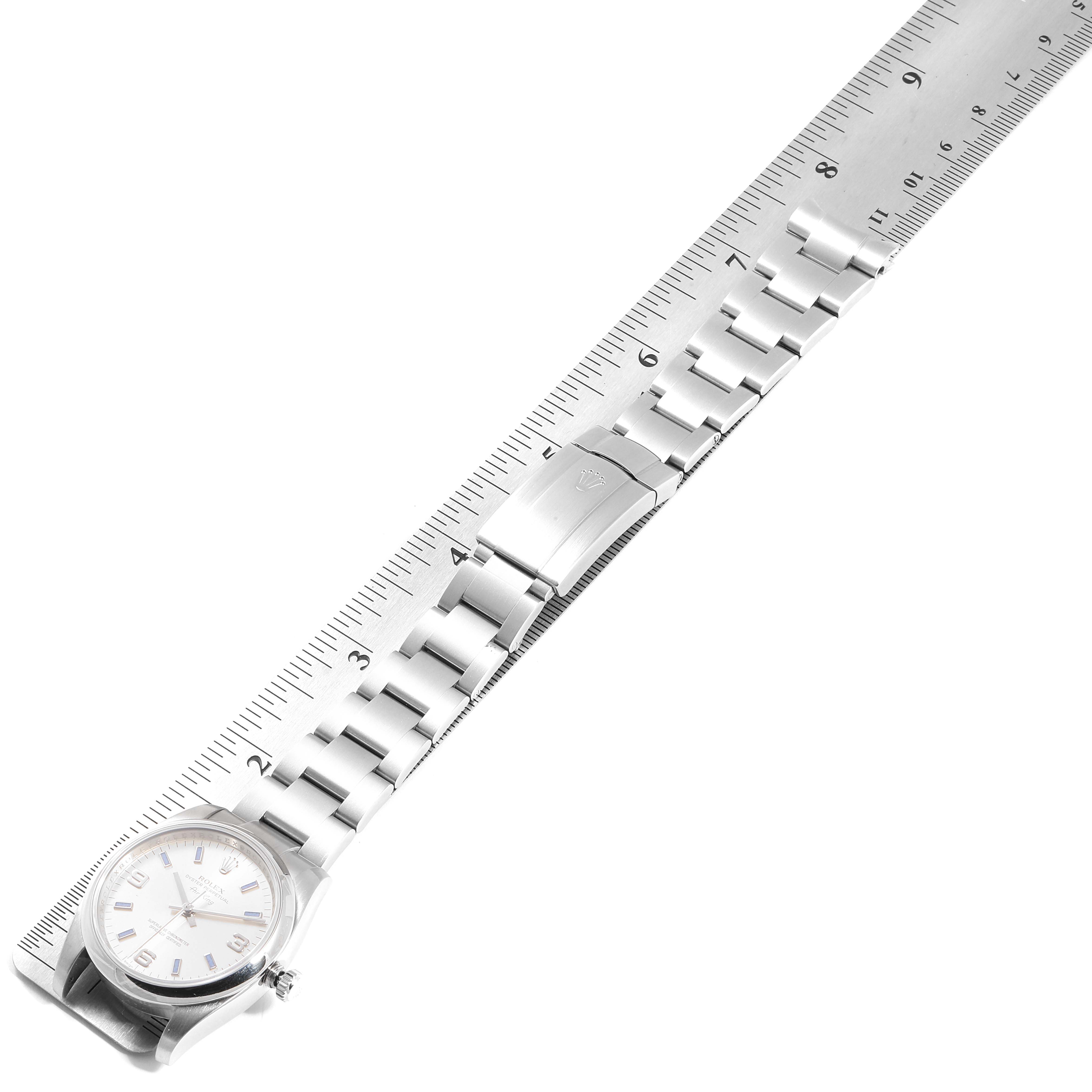 The Rolex Air-King 114200 Men's Stainless Steel Silver Dial 114200 Men's Stainless Steel Silver Dial watch is shown in a flat position with a visible dial, bracelet, and clasp next to a ruler for scale.