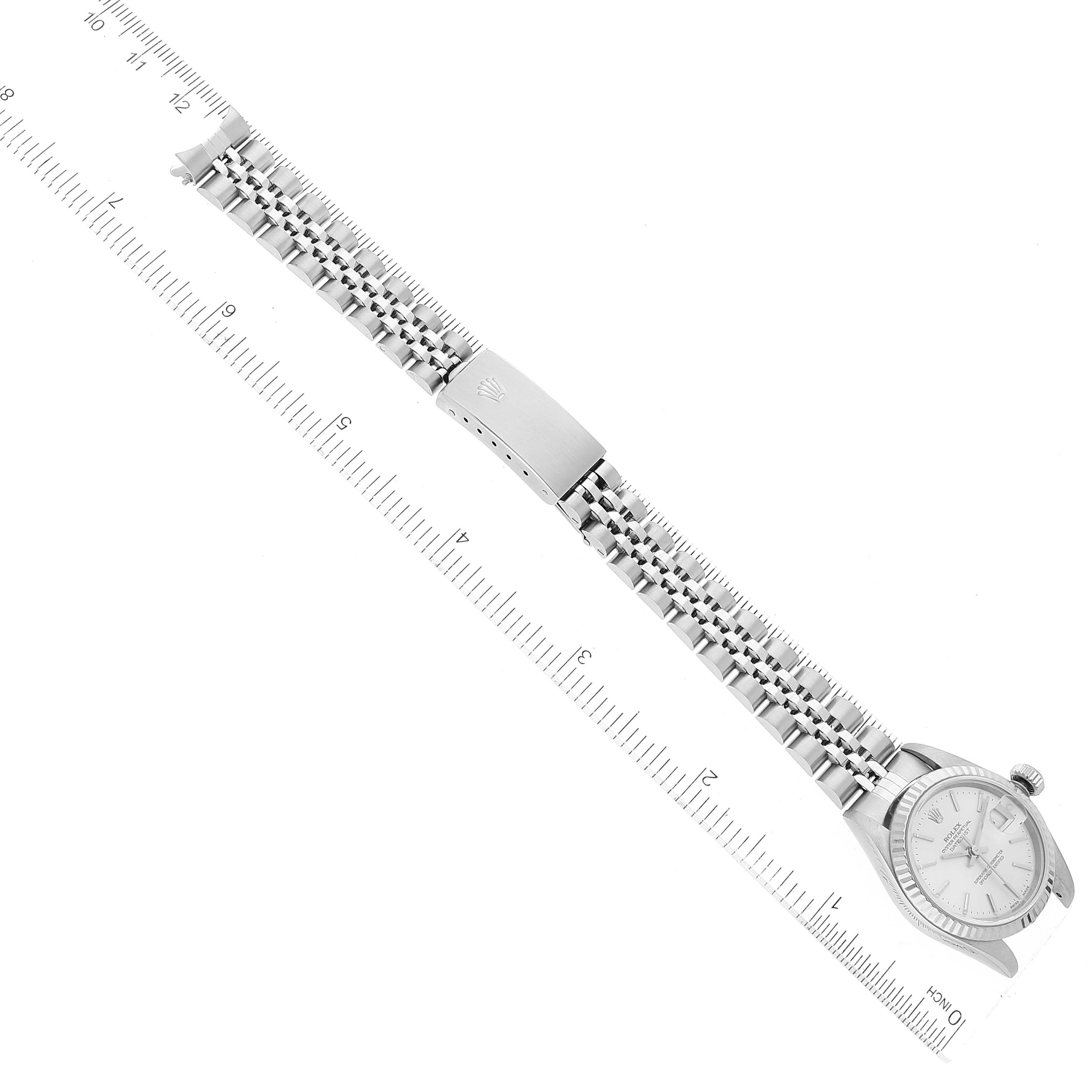 The image shows a Rolex Datejust 79174 Women's Stainless Steel Silver Dial 79174 Women's Stainless Steel Silver Dial watch laid flat displaying the face, bezel, bracelet, and clasp, with a ruler for scale.