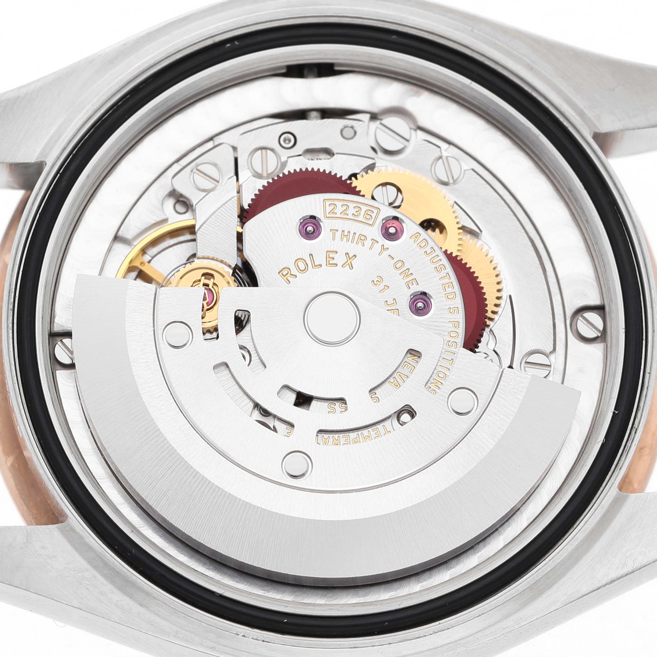 The image shows the movement of a mid-size Rolex watch with parts like the rotor and gears visible from the back.