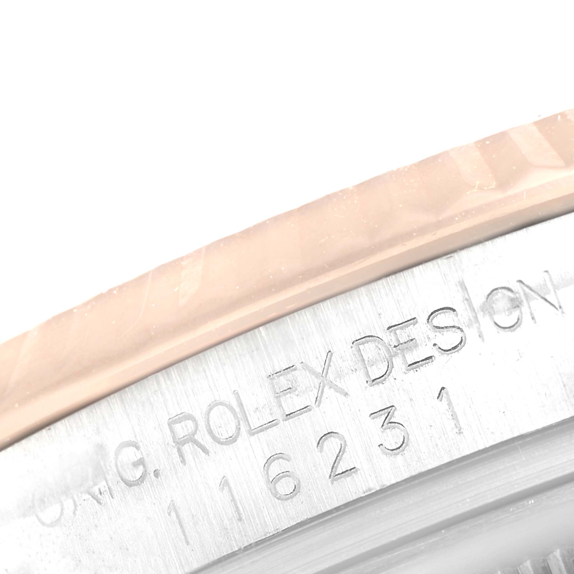 The image shows an extreme close-up of the edge of a Rolex Datejust 116231 Men
s Steel and Gold (two tone) Silver Dial 116231 Men
s Steel and Gold (two tone) Silver Dial watch case, featuring engraved text.