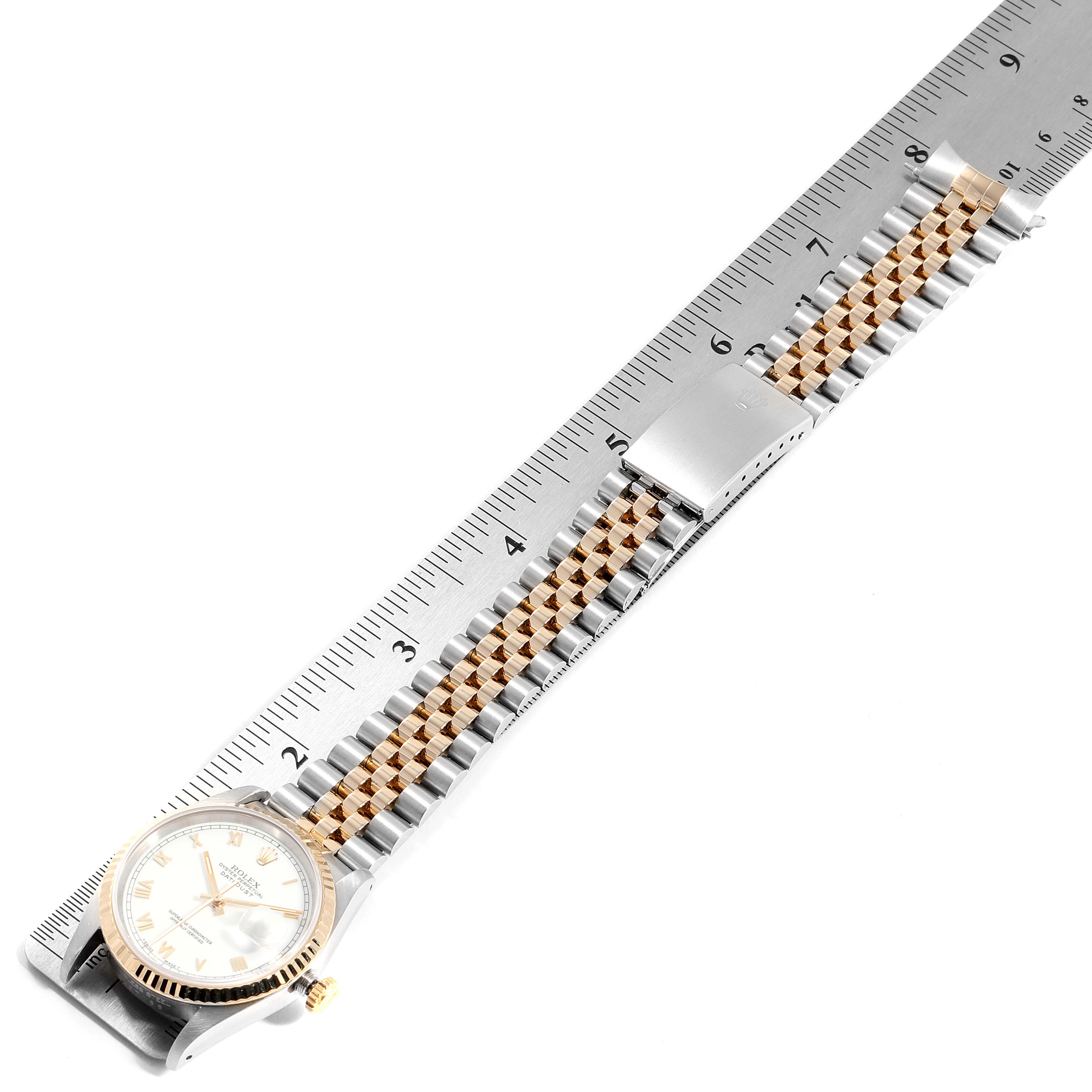 This image shows the Rolex Datejust 16233 Men
s Steel and Gold (two tone) White Dial 16233 Men
s Steel and Gold (two tone) White Dial watch laid flat next to a ruler, showcasing its bracelet and face.