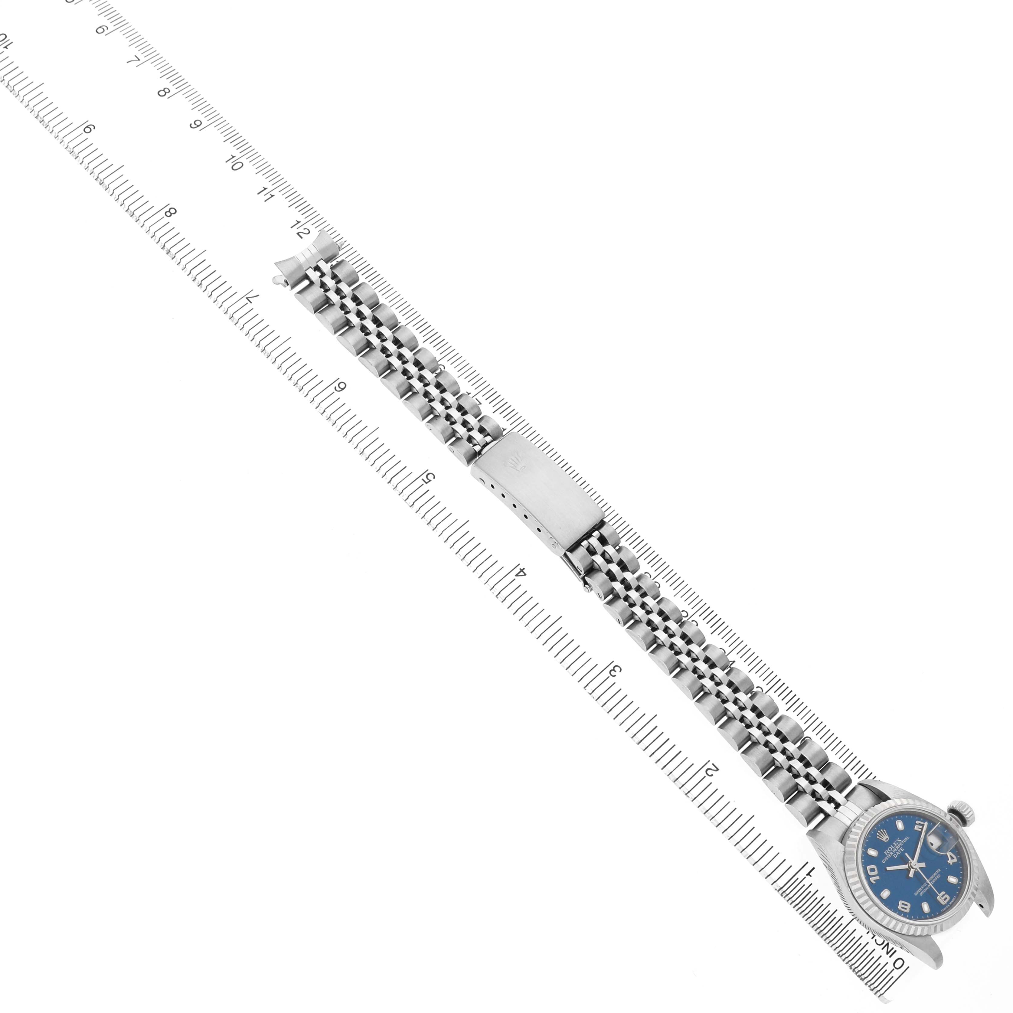 The image shows a Rolex Datejust 79174 Women's Stainless Steel Blue Dial watch displayed alongside a ruler, highlighting the band and clasp, viewed from above.