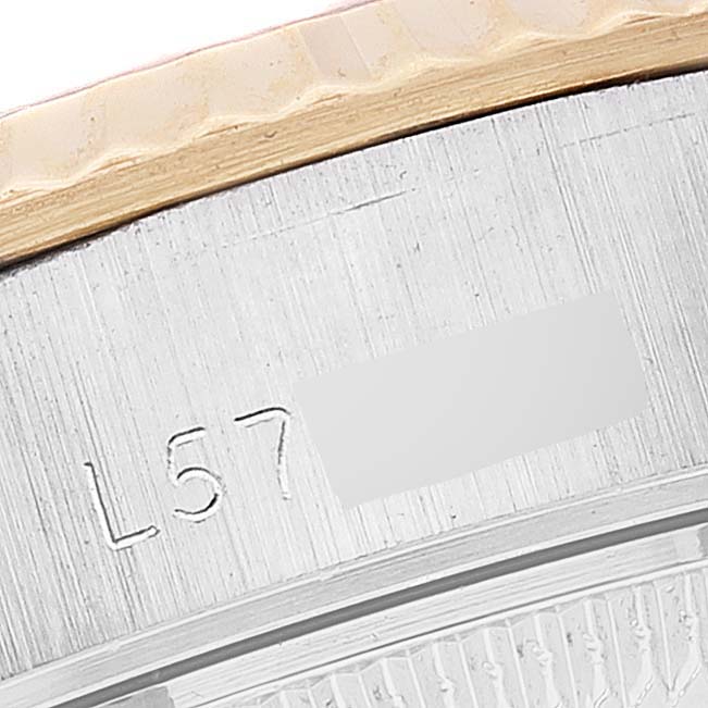 This close-up image of a Rolex Datejust 69173 Women's Steel and Gold (two tone) White Dial 69173 Women's Steel and Gold (two tone) White Dial watch shows its fluted bezel and part of its engraved caseback.