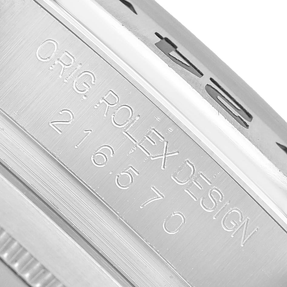 The image shows the side of a Rolex Explorer 216570 Men's Stainless Steel Black Dial watch case, featuring engraved text and a visible model number.