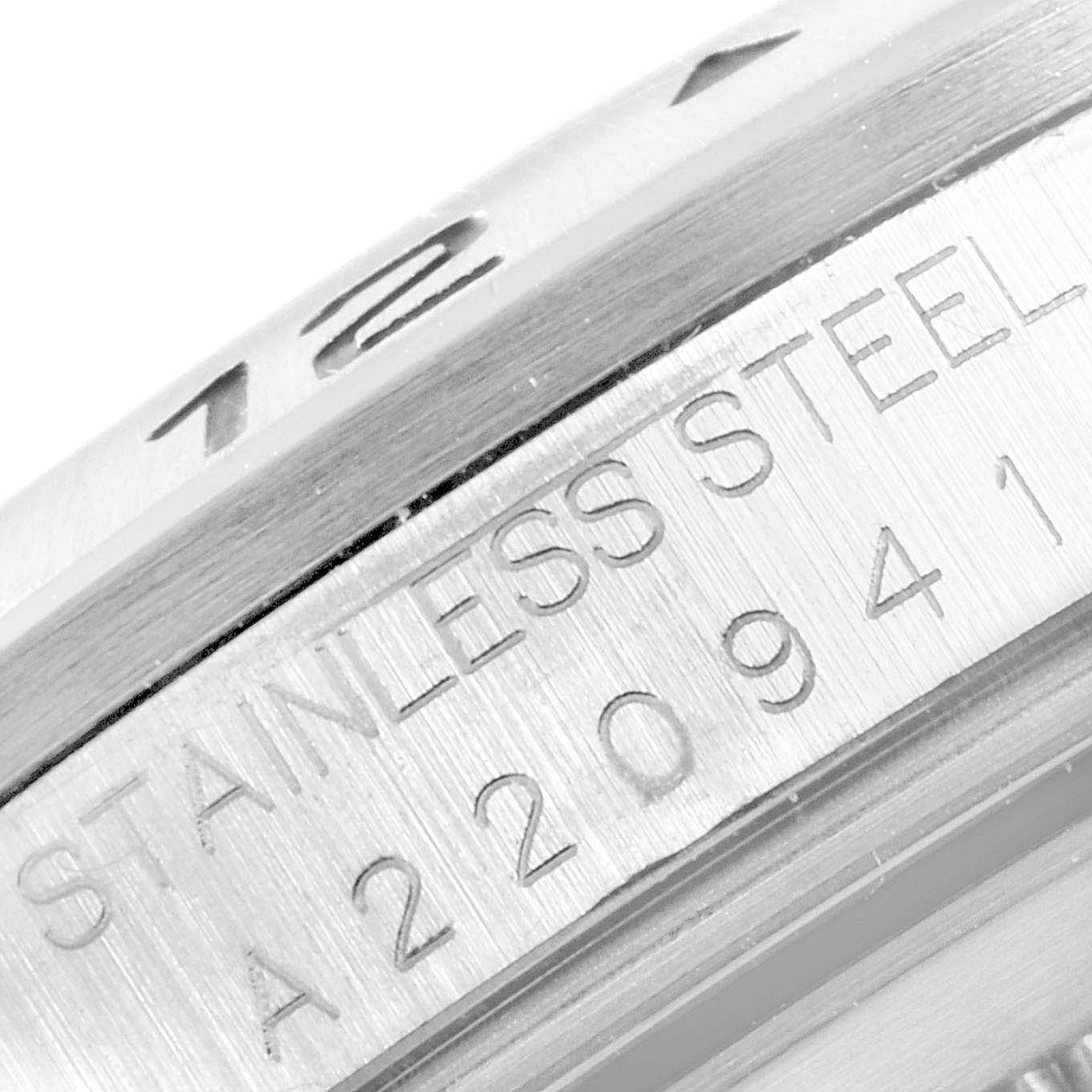 The image shows a close-up of the Rolex Explorer 16570 Men
s Stainless Steel White Dial 16570 Men
s Stainless Steel White Dial
s bezel and engraved serial number.