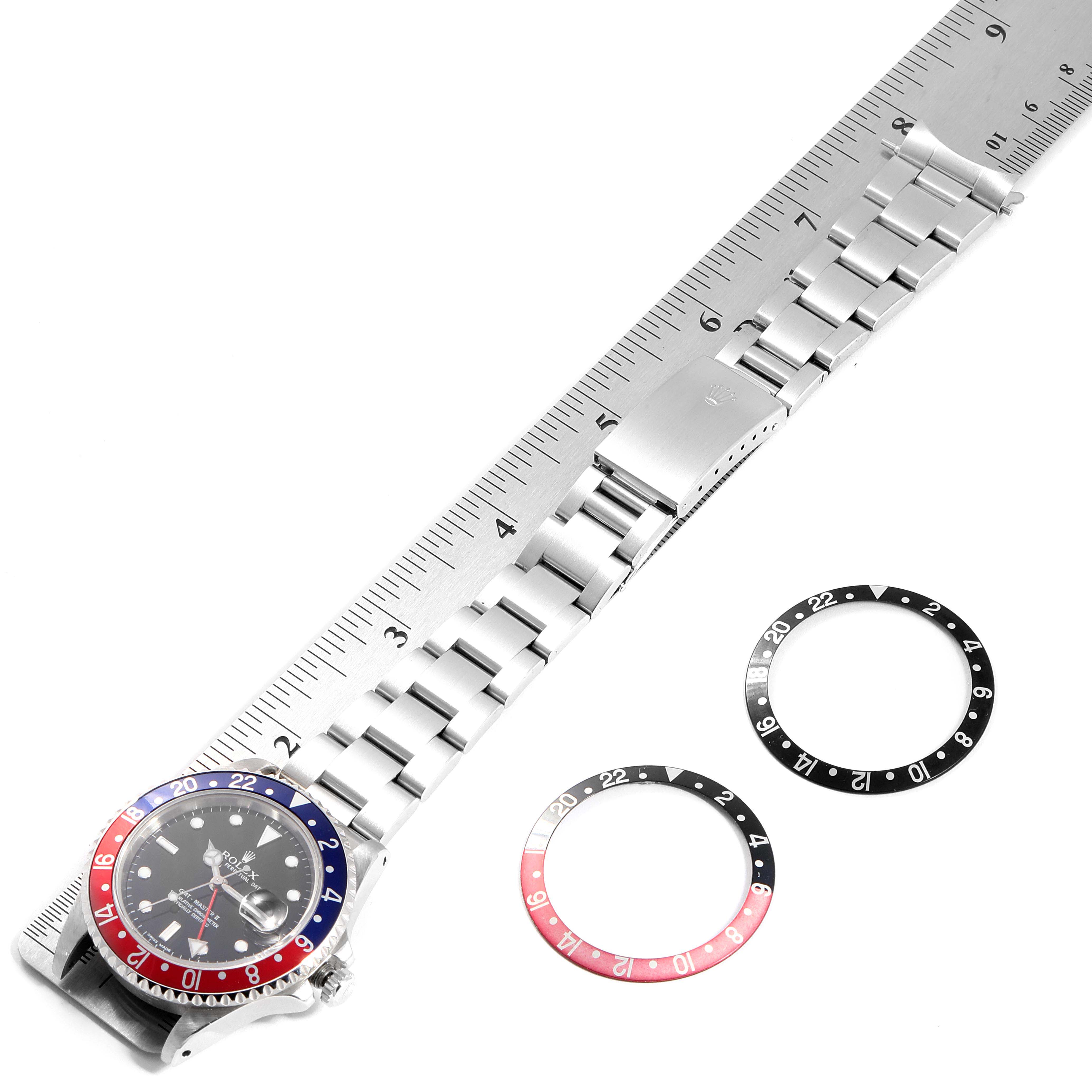 This image shows a top-down view of a Rolex GMT-Master 16710 Men's Stainless Steel Black Dial 16710 Men's Stainless Steel Black Dial with its bracelet and additional bezel inserts.