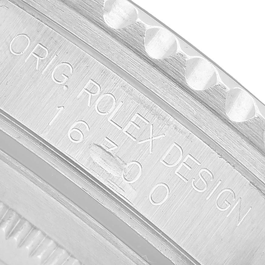 The image shows a close-up of the bezel and engraved case side of a Rolex GMT-Master 16700 Men's Stainless Steel Black Dial, displaying "ROLEX DESIGN" and a model number.