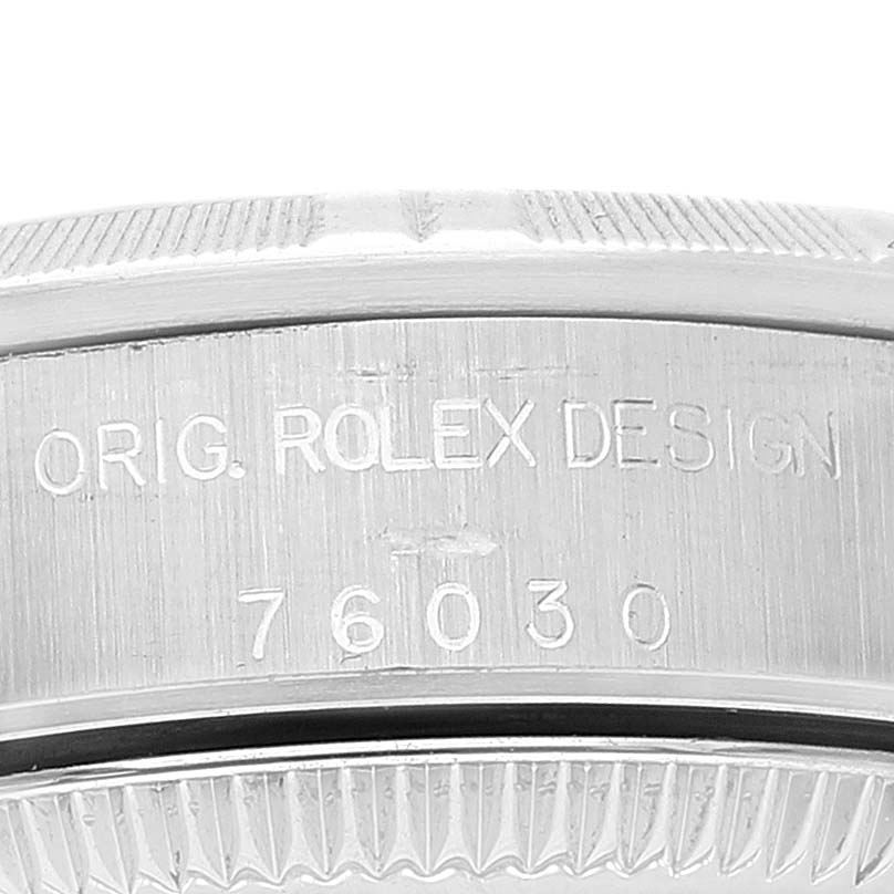 This close-up image captures the engraved case back of a Rolex Oyster Perpetual 76030 Women
s Stainless Steel White Dial 76030 Women
s Stainless Steel White Dial watch showing its model number and the words "ORIG. ROLEX DESIGN."
