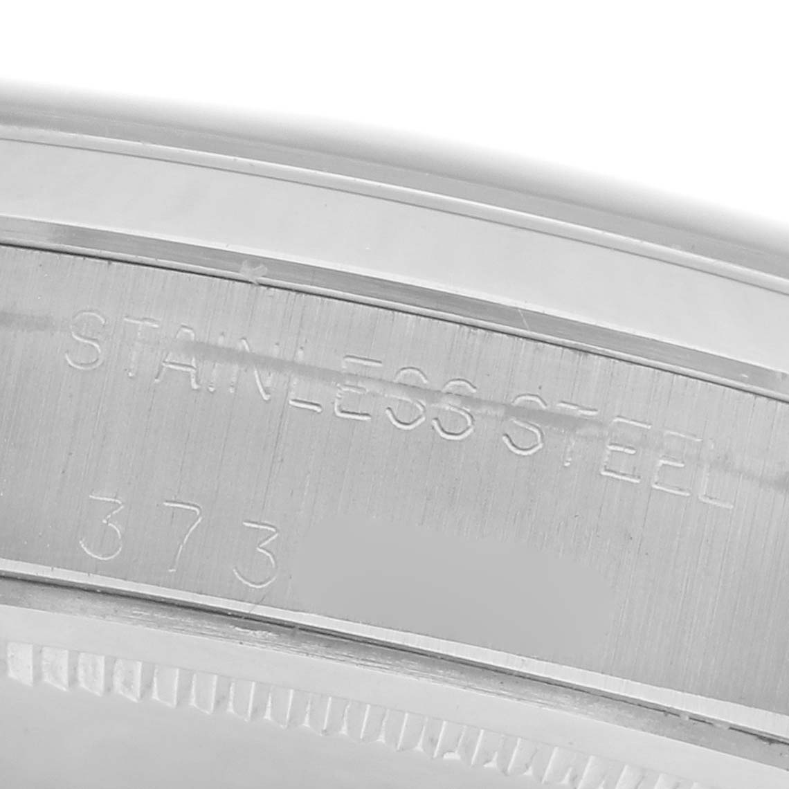 The image shows a close-up of the stainless steel bezel of a Rolex Date 6694 Men's Stainless Steel Silver Dial 6694 Men's Stainless Steel Silver Dial model watch with engraved text.