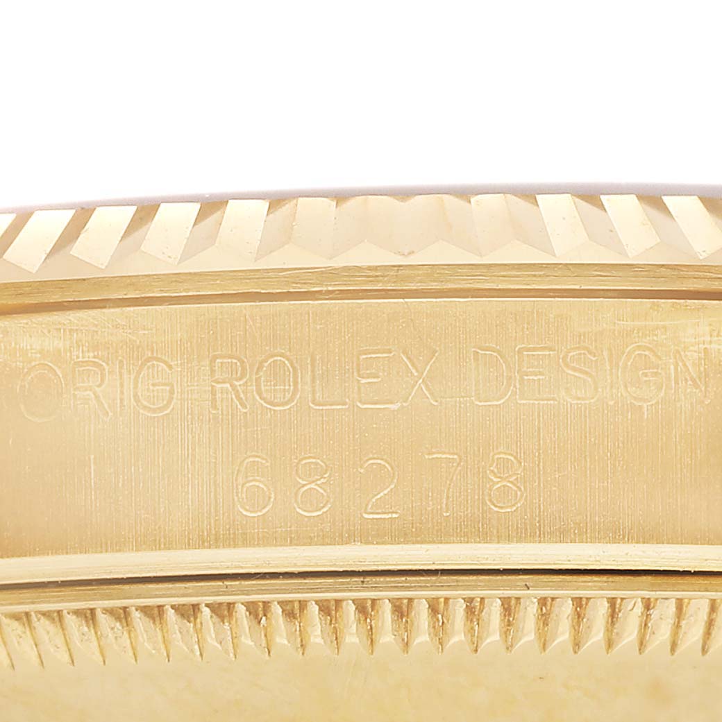 The image shows a close-up of the side of a Rolex Datejust 68278 Women's Yellow Gold White Dial watch, highlighting its case engraving and fluted bezel.