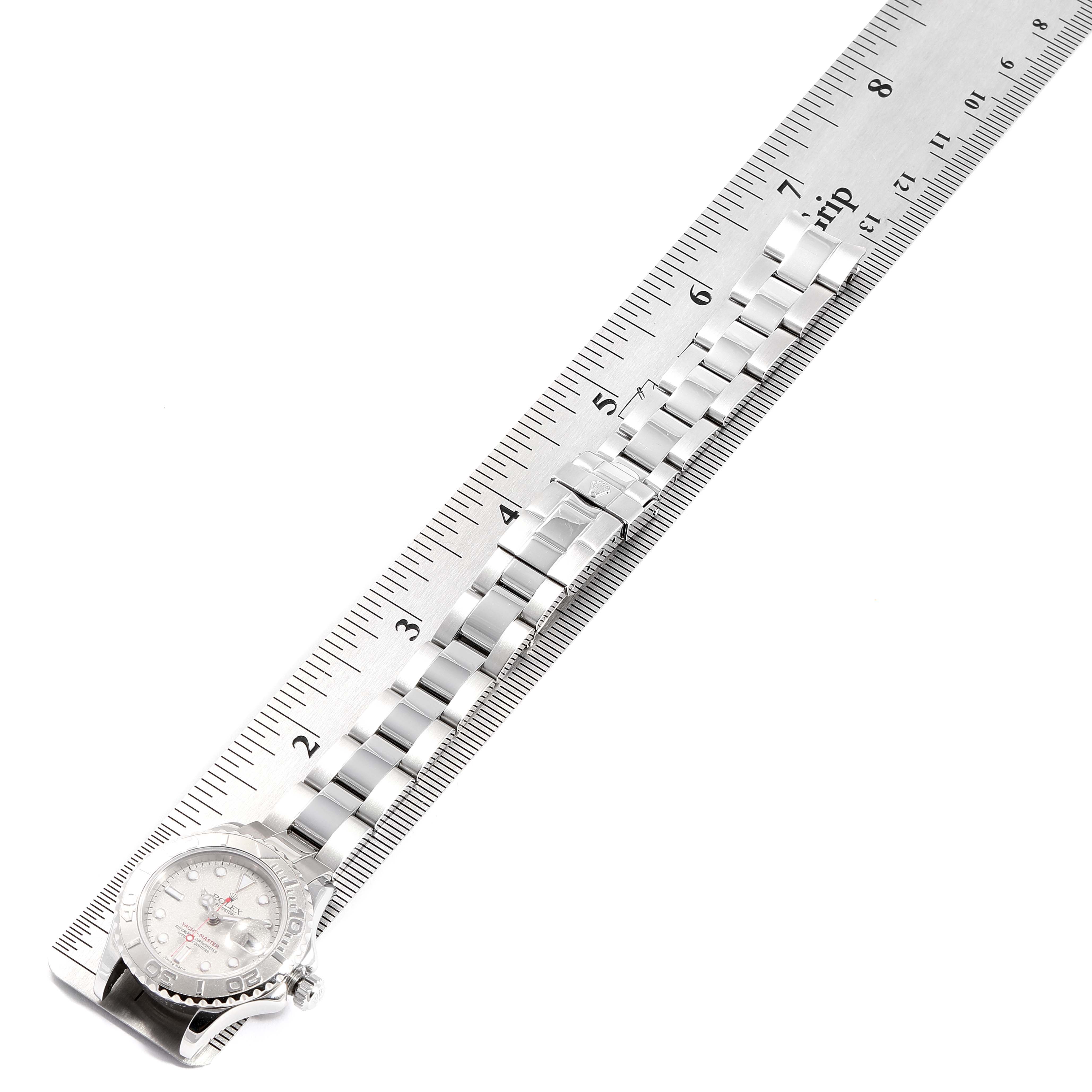 The shown Rolex Yacht-Master 169622 Women's Stainless Steel Silver Dial 169622 Women's Stainless Steel Silver Dial watch is taken from an aerial view, highlighting its metal bracelet next to a ruler.