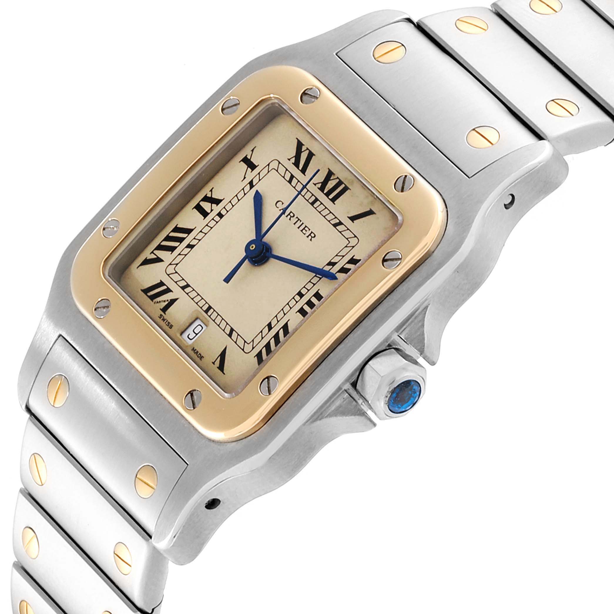 This image shows the face, bezel, crown, and part of the bracelet of the Cartier Santos 187901 Men
s Steel and Gold (two tone) Beige Dial 187901 Men
s Steel and Gold (two tone) Beige Dial watch from an angled view.