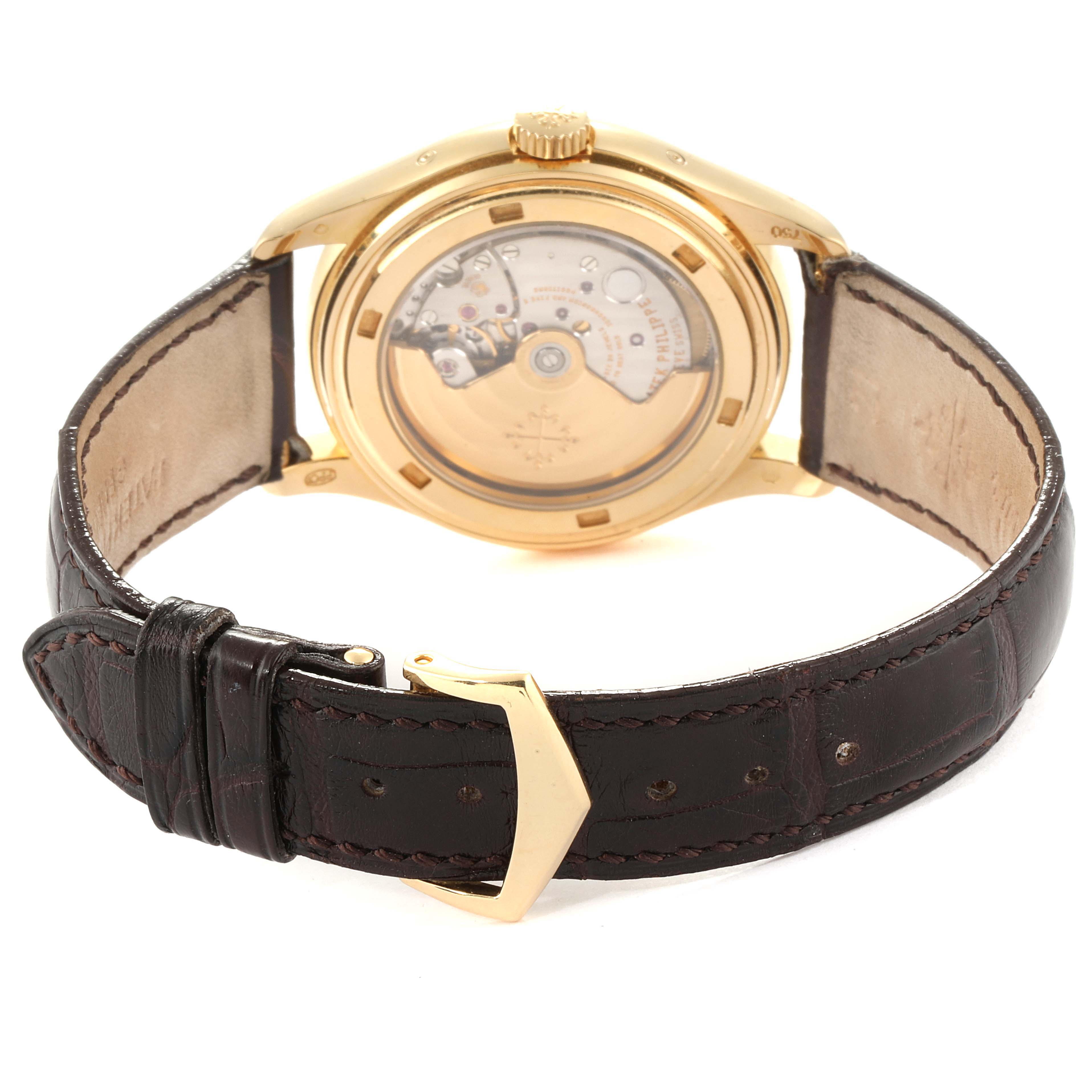 The image shows the back view of a Patek Philippe 5146J Men's Yellow Gold Beige Dial 5146J Men's Yellow Gold Beige Dial Complicated Annual Calendar Yellow Gold Mens Watch 5146, highlighting its open case back and strap.