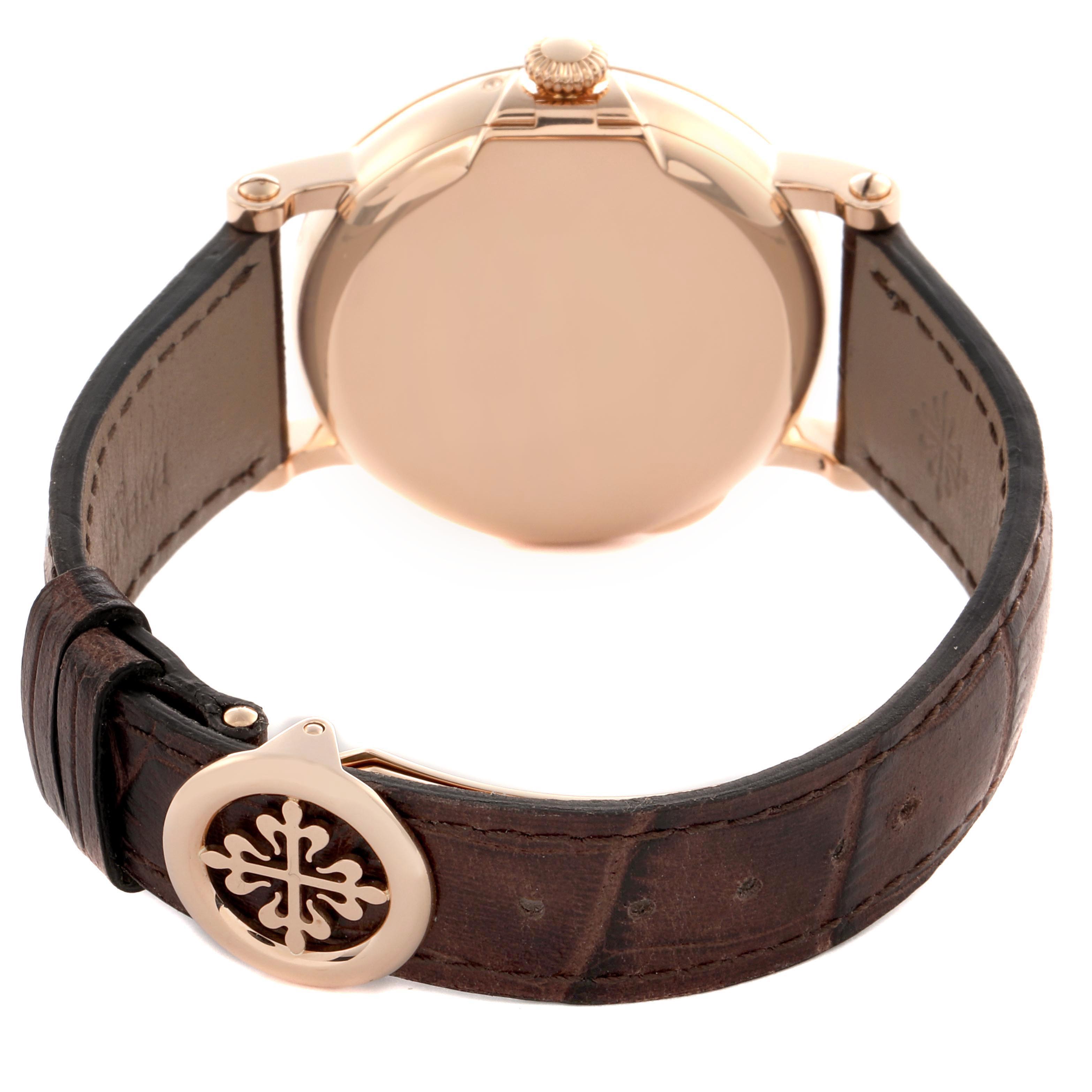 The Patek Philippe Complications 5159J-001 Men's Rose Gold White Dial 5159J-001 Men's Rose Gold White Dial watch is shown from a rear angle, displaying the back case, crown, and leather strap with logo clasp.