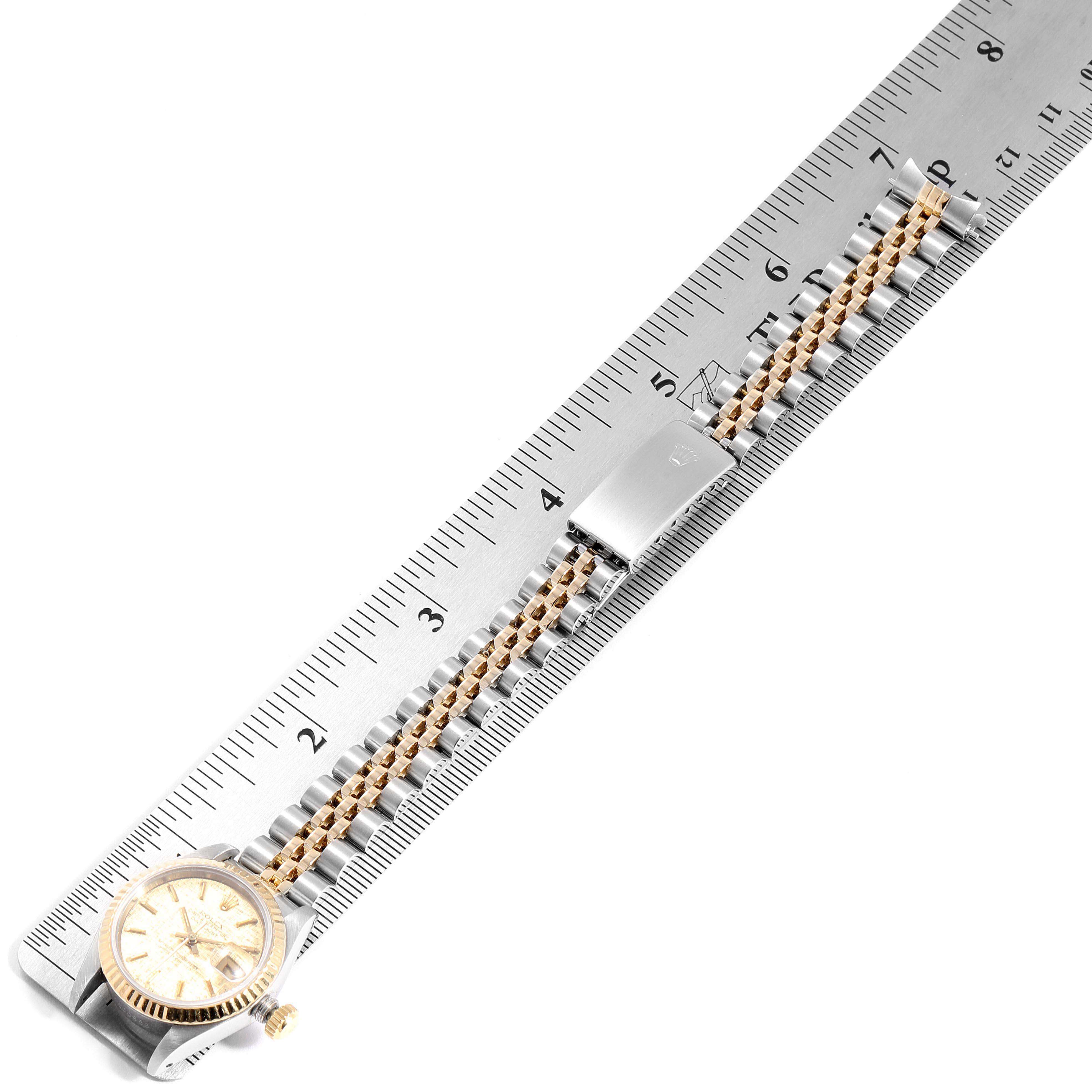 The Rolex Datejust 69173 Women's Steel and Gold (two tone) Champagne Dial 69173 Women's Steel and Gold (two tone) Champagne Dial watch is shown from a top view, highlighting its face and full bracelet laid next to a ruler for measurement.