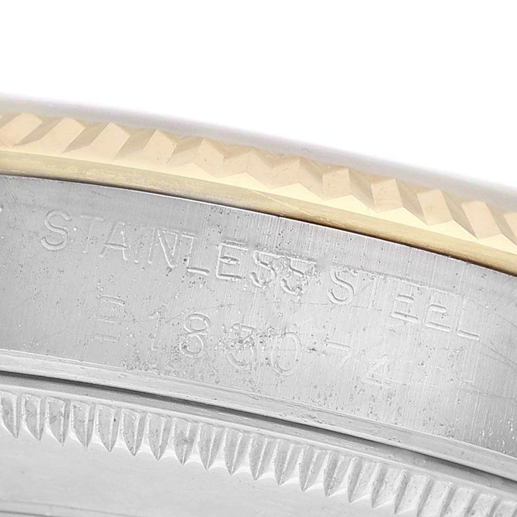 The image shows a close-up of a Rolex Mid-Size 68273 Women's Steel and Gold (two tone) White Dial watch, highlighting the engraved stainless steel case and textured bezel.