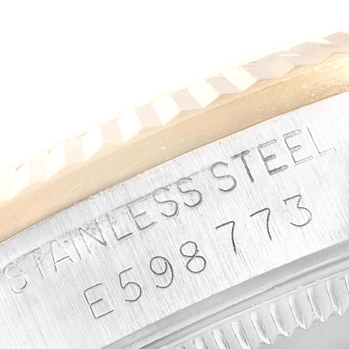 This close-up image of a Rolex Mid-Size 68273 Women
s Steel and Gold (two tone) Champagne Dial 68273 Women
s Steel and Gold (two tone) Champagne Dial watch shows part of the bezel and the stainless steel casing with an engraved serial number.