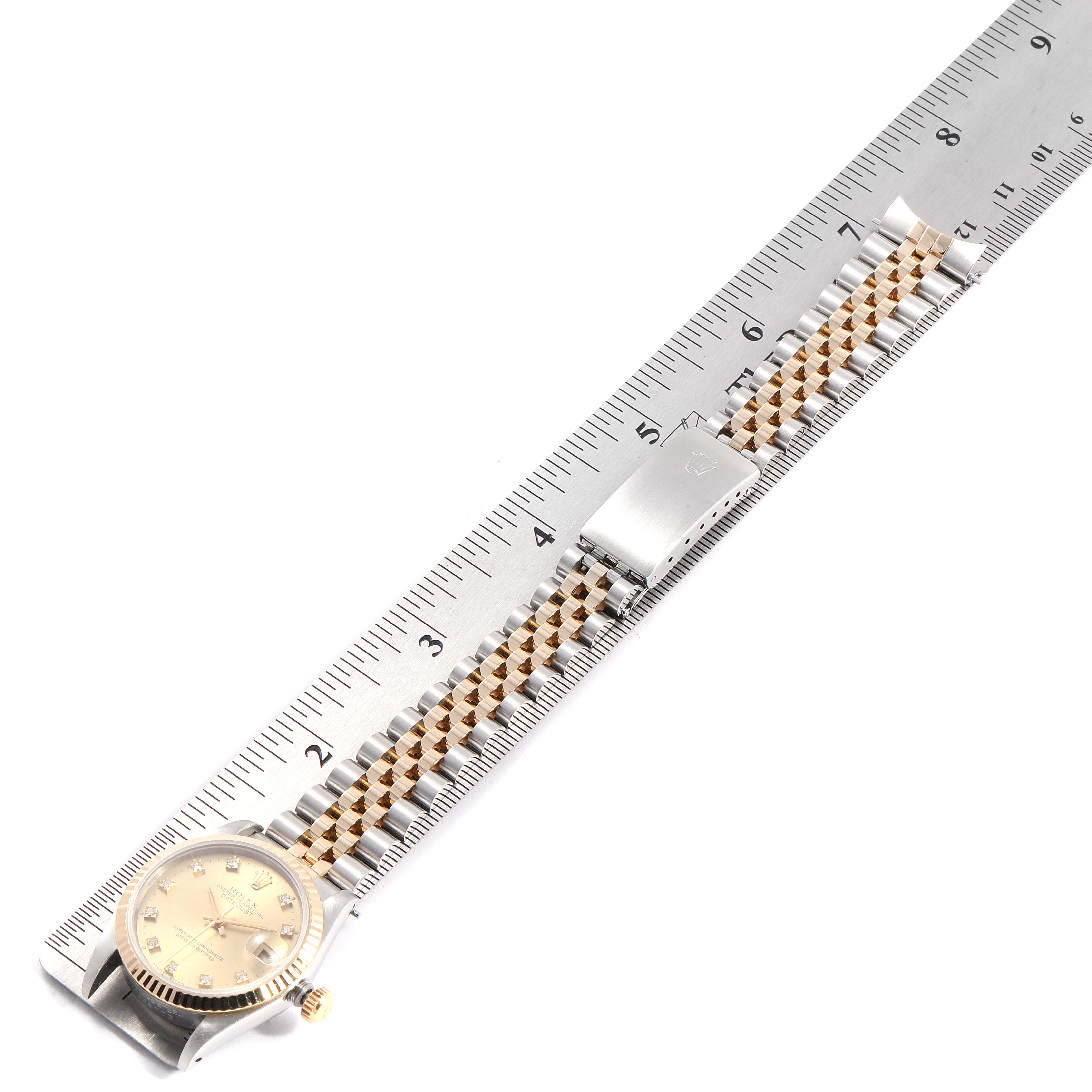 This image shows a Rolex Mid-Size 68273 Women
s Steel and Gold (two tone) Champagne Dial 68273 Women
s Steel and Gold (two tone) Champagne Dial watch displayed flat next to a ruler, highlighting the dial, bracelet, and clasp.