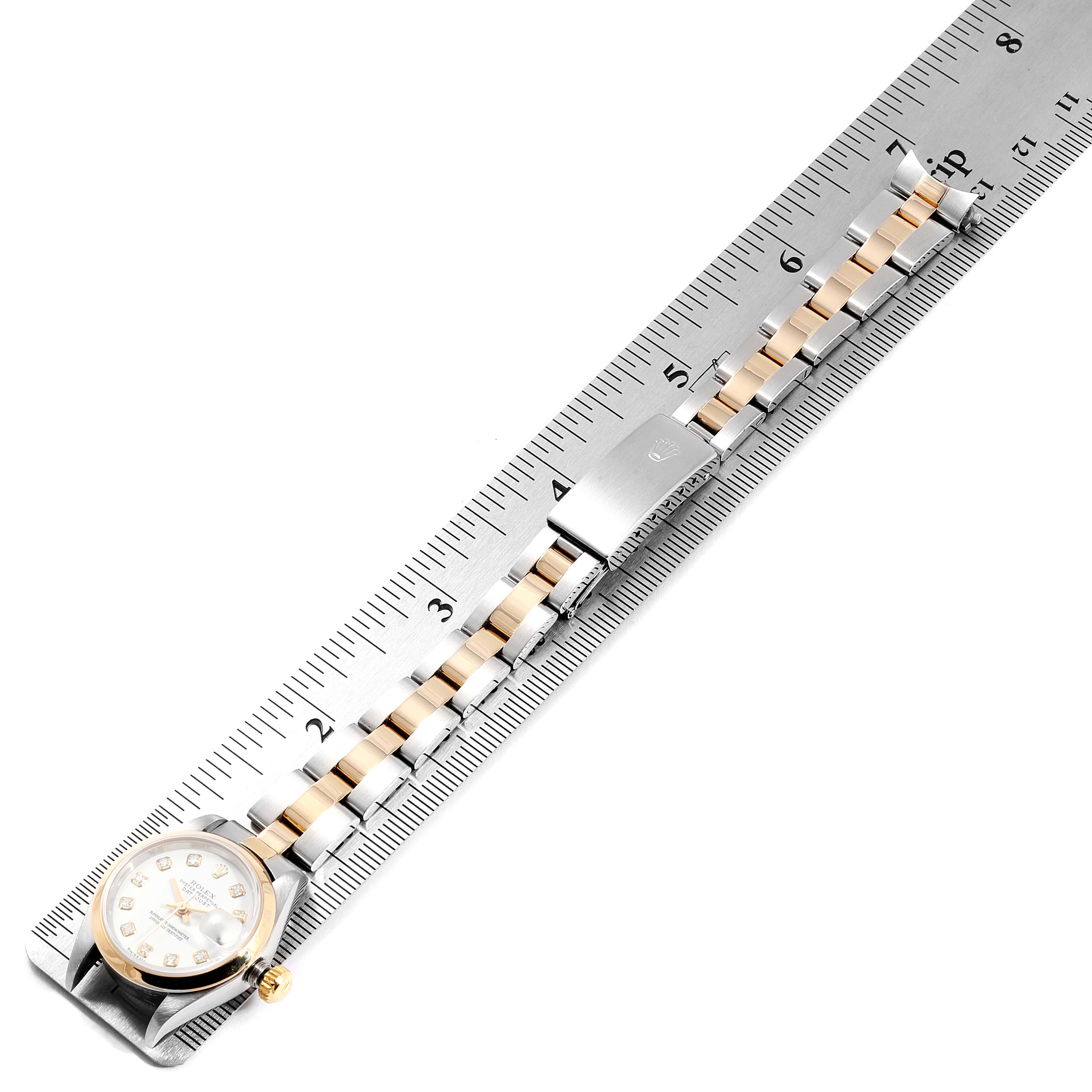 The image shows a Rolex Datejust 79163 Women's Steel and Gold (two tone) White Dial 79163 Women's Steel and Gold (two tone) White Dial watch laid flat on a ruler, highlighting its bracelet and clasp.