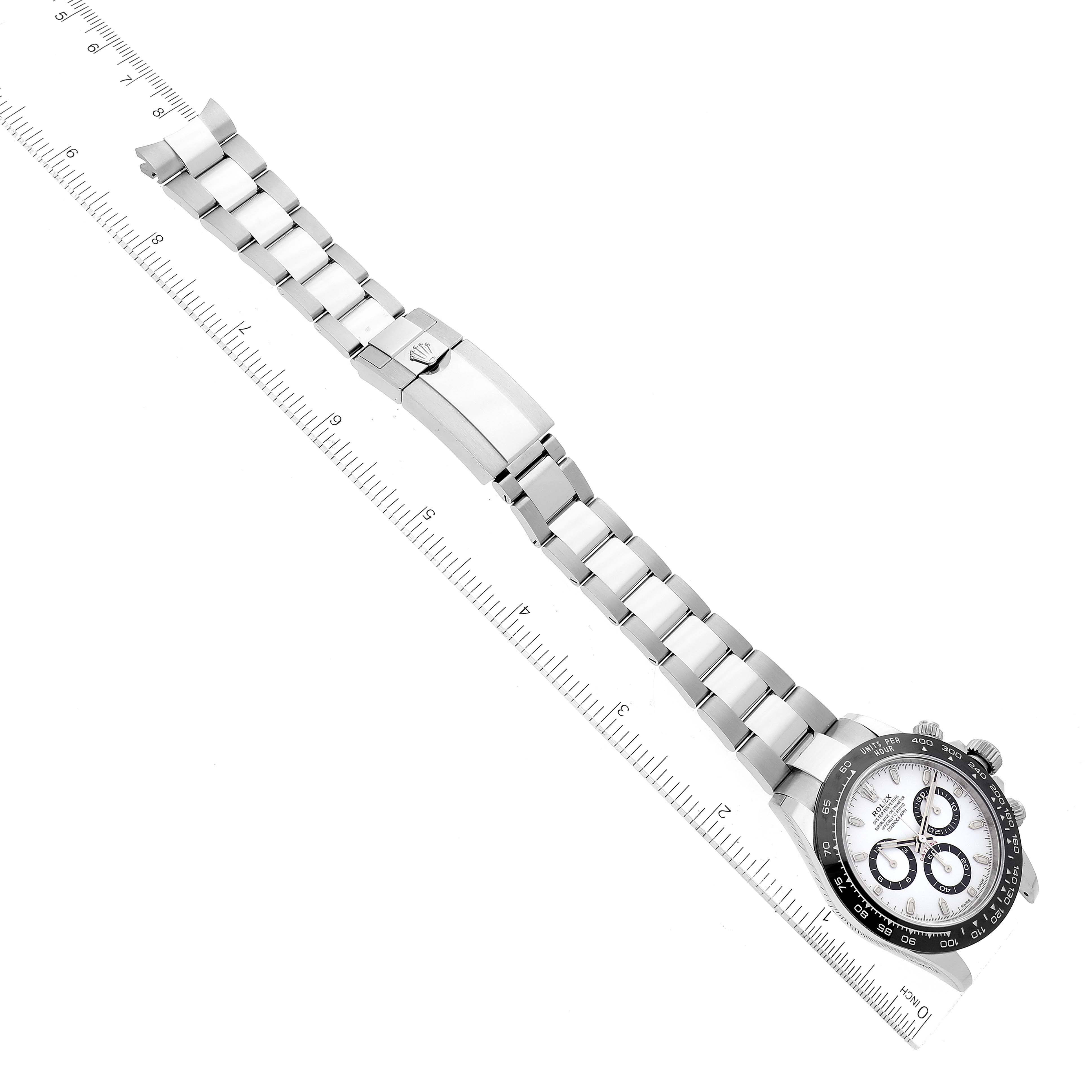 This image shows a Rolex Daytona 116500 Men's Stainless Steel White Dial 116500 Men's Stainless Steel White Dial watch laid flat with a ruler measuring the length of its bracelet and clasp.