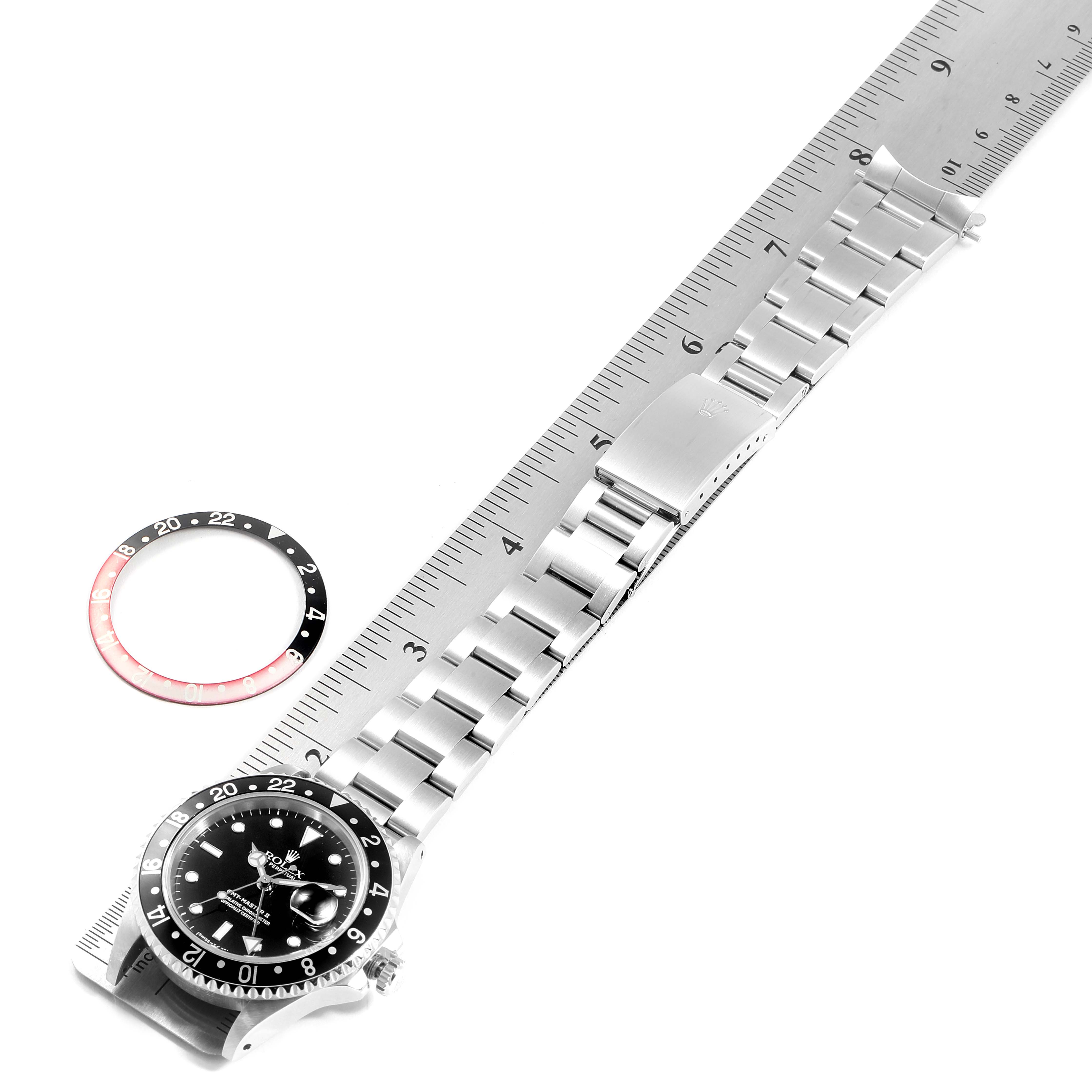 The image shows a Rolex GMT-Master 16710 Men
s Stainless Steel Black Dial 16710 Men
s Stainless Steel Black Dial watch laid flat next to a ruler and a separate bezel insert.