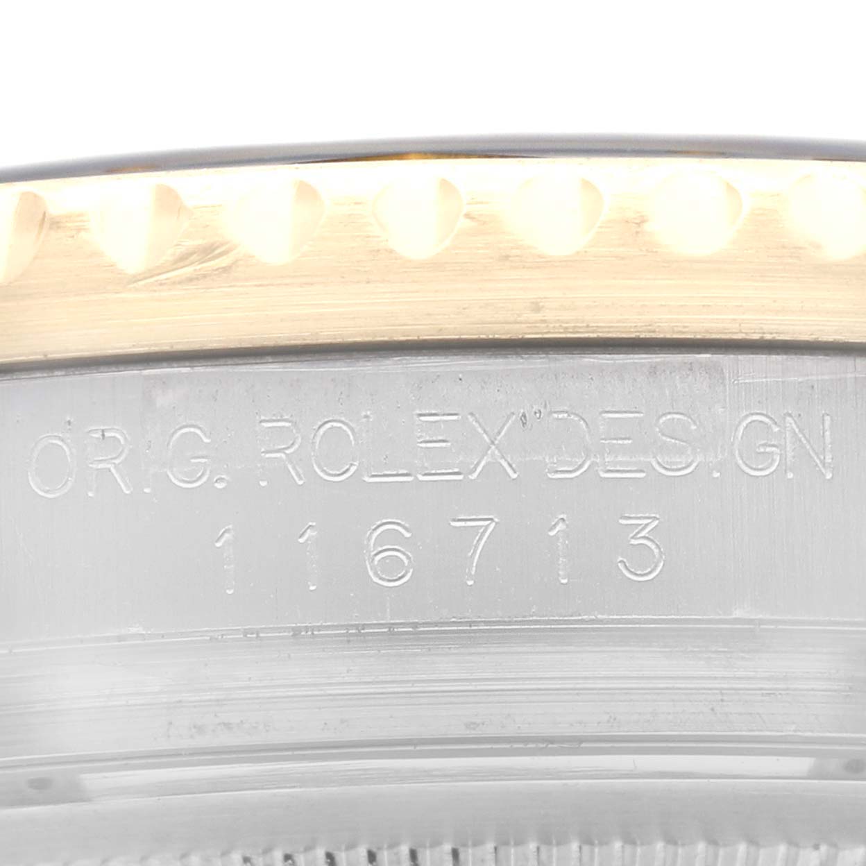 This image shows the engraved model number and part of the bezel of a Rolex GMT-Master 116713 Men's Steel and Gold (two tone) Black Dial 116713 Men's Steel and Gold (two tone) Black Dial watch.