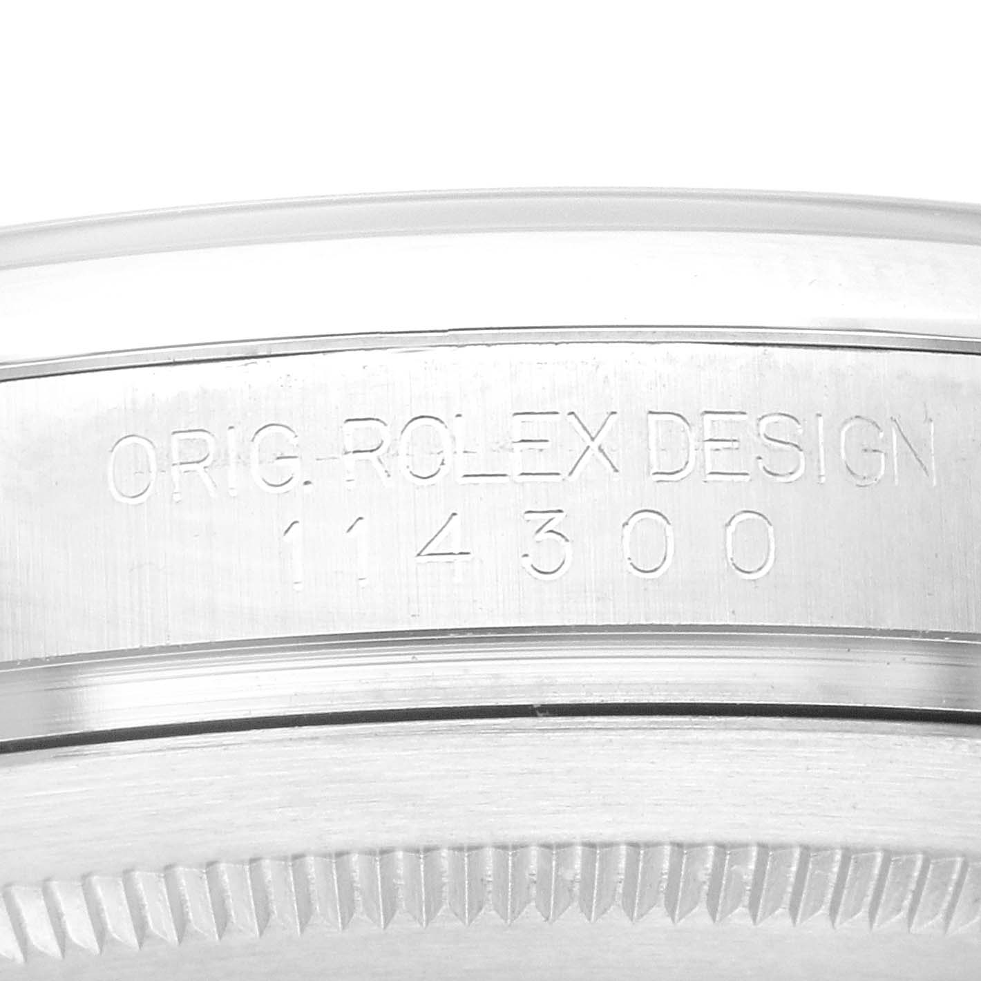 This image shows a close-up of the engraved side of the case of a Rolex Oyster Perpetual 114300 Men
s Stainless Steel Black Dial 114300 Men
s Stainless Steel Black Dial model, displaying the model number 114300.