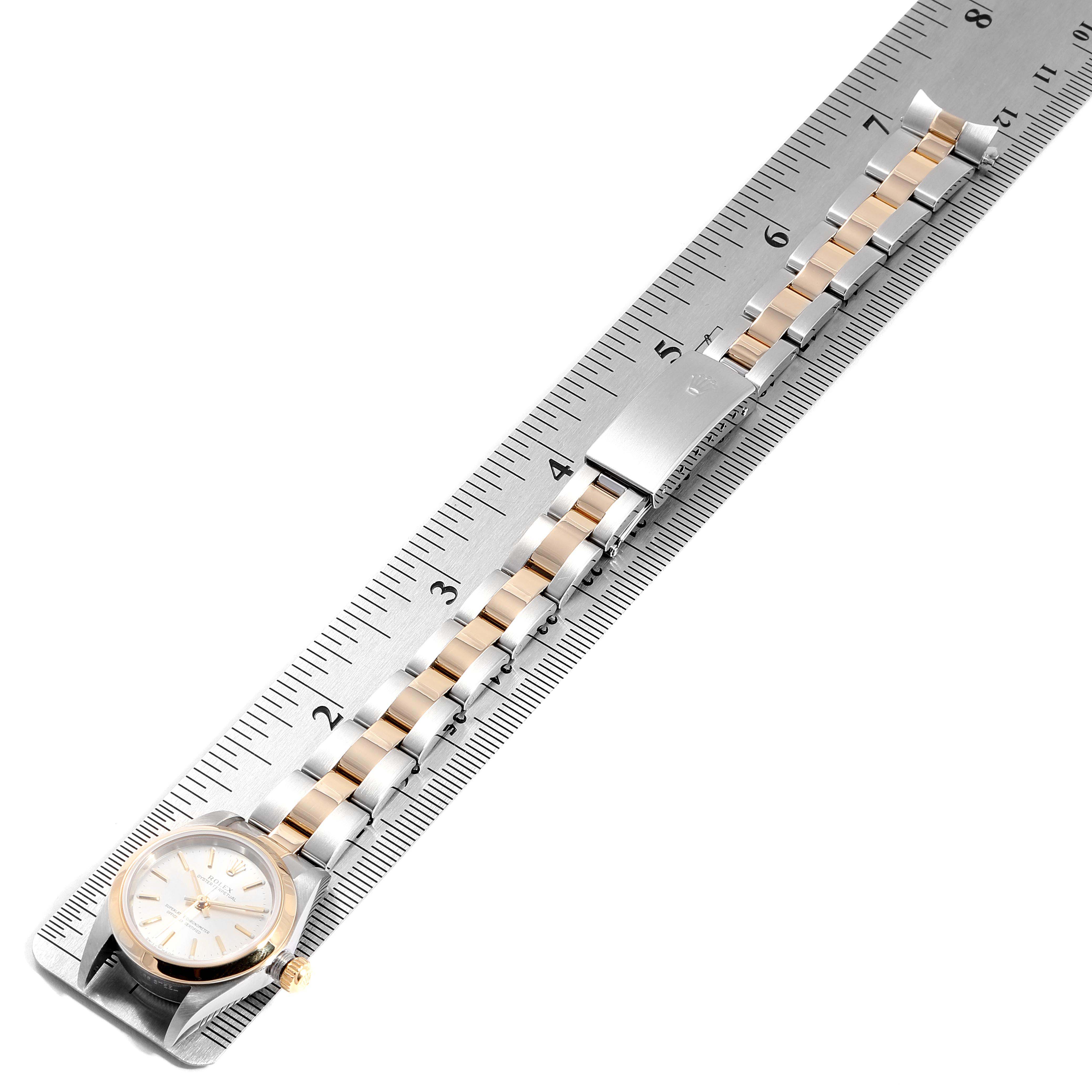 The image shows a Rolex Oyster Perpetual 76183 Women's Steel and Gold (two tone) Silver Dial 76183 Women's Steel and Gold (two tone) Silver Dial watch laid flat against a ruler, highlighting its dial and bracelet.