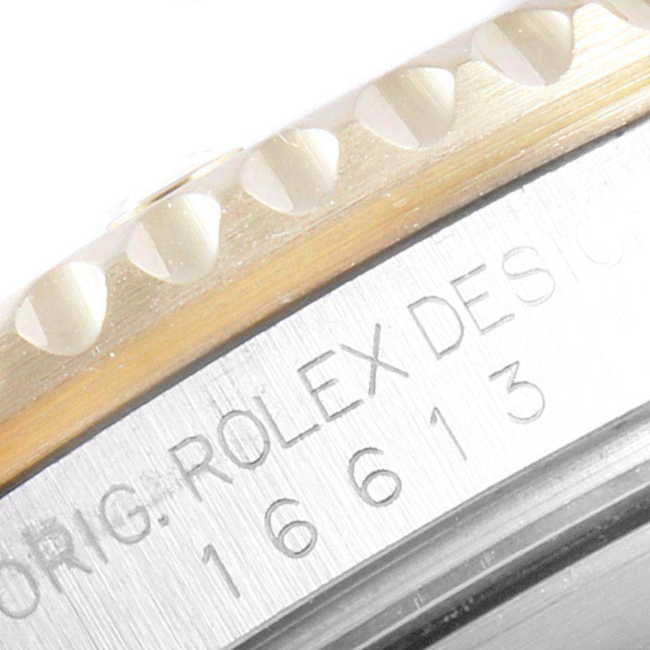 The image shows a close-up detail of the bezel and case with engravings on a Rolex Submariner 16613 Men
s Steel and Gold (two tone) Blue Dial 16613 Men
s Steel and Gold (two tone) Blue Dial model watch.