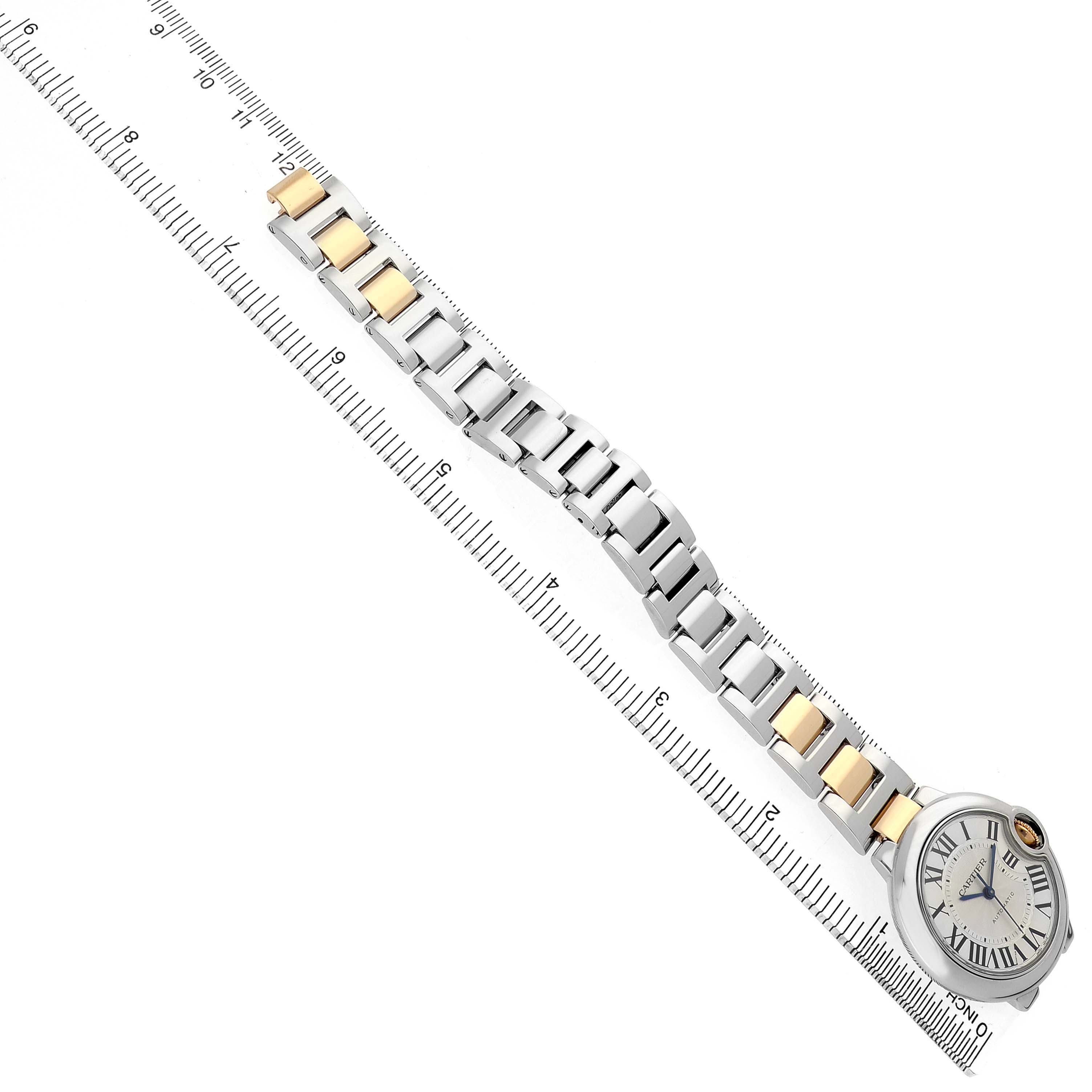The Cartier Ballon Bleu W2BB0002 Women's Stainless Steel Silver Dial watch is shown at a top-down angle with its face and two-tone bracelet visible next to a ruler.