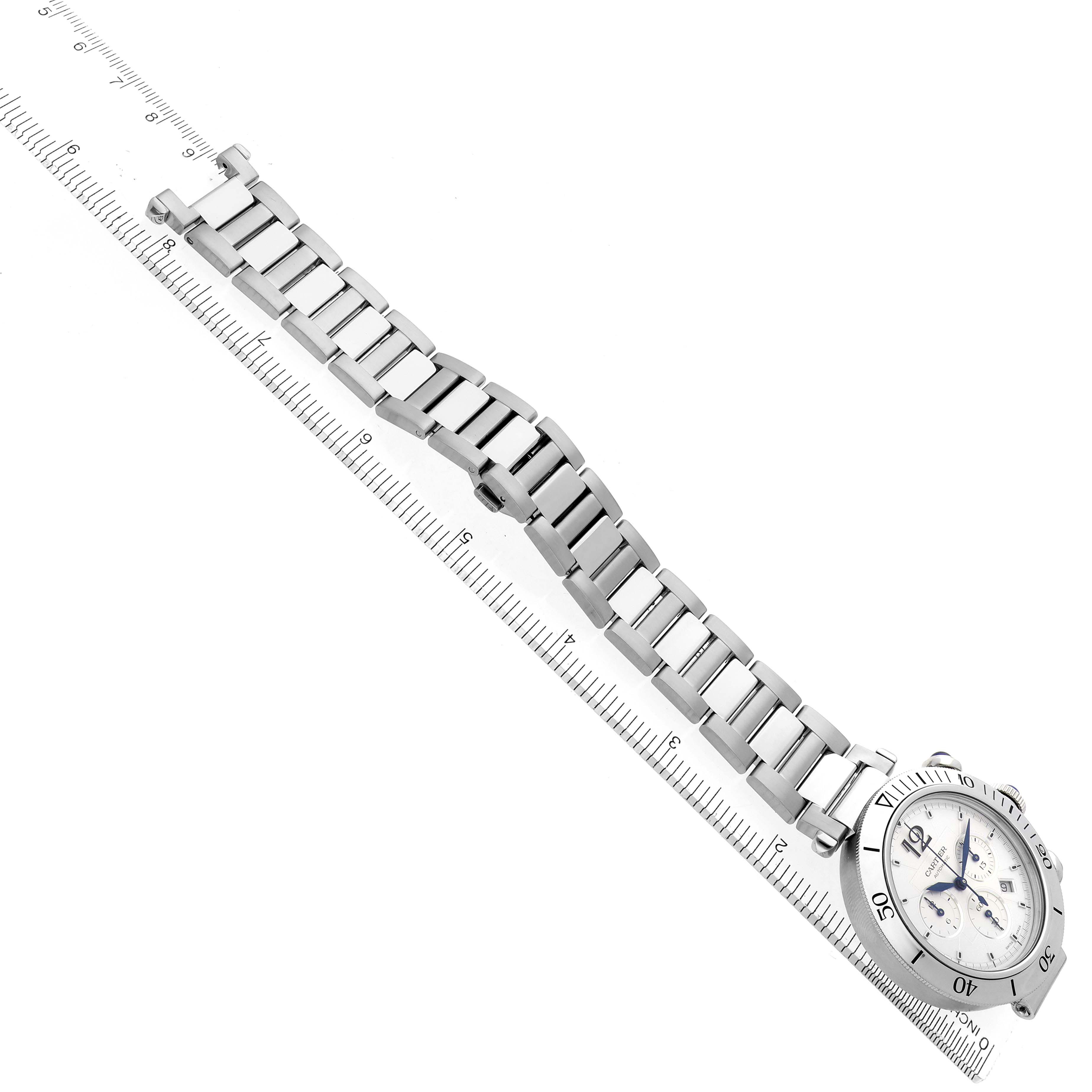 The Cartier Pasha WSPA0018 Men
s Stainless Steel Silver Dial WSPA0018 Men
s Stainless Steel Silver Dial watch is shown at an angle showcasing its face and metal bracelet resting on a ruler.
