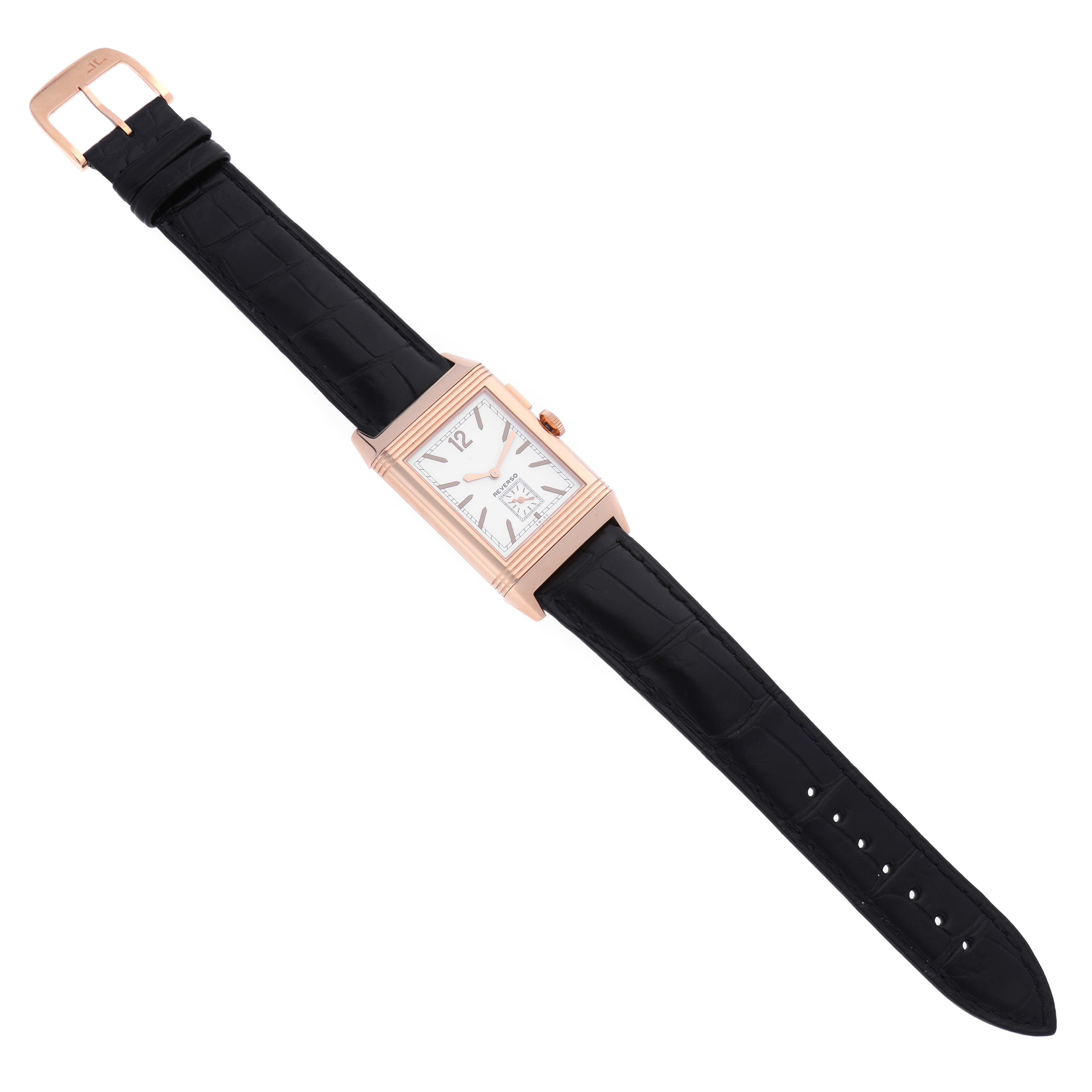 The Jaeger-LeCoultre Reverso watch is shown from an overhead angle, displaying the watch face, case, and full strap.