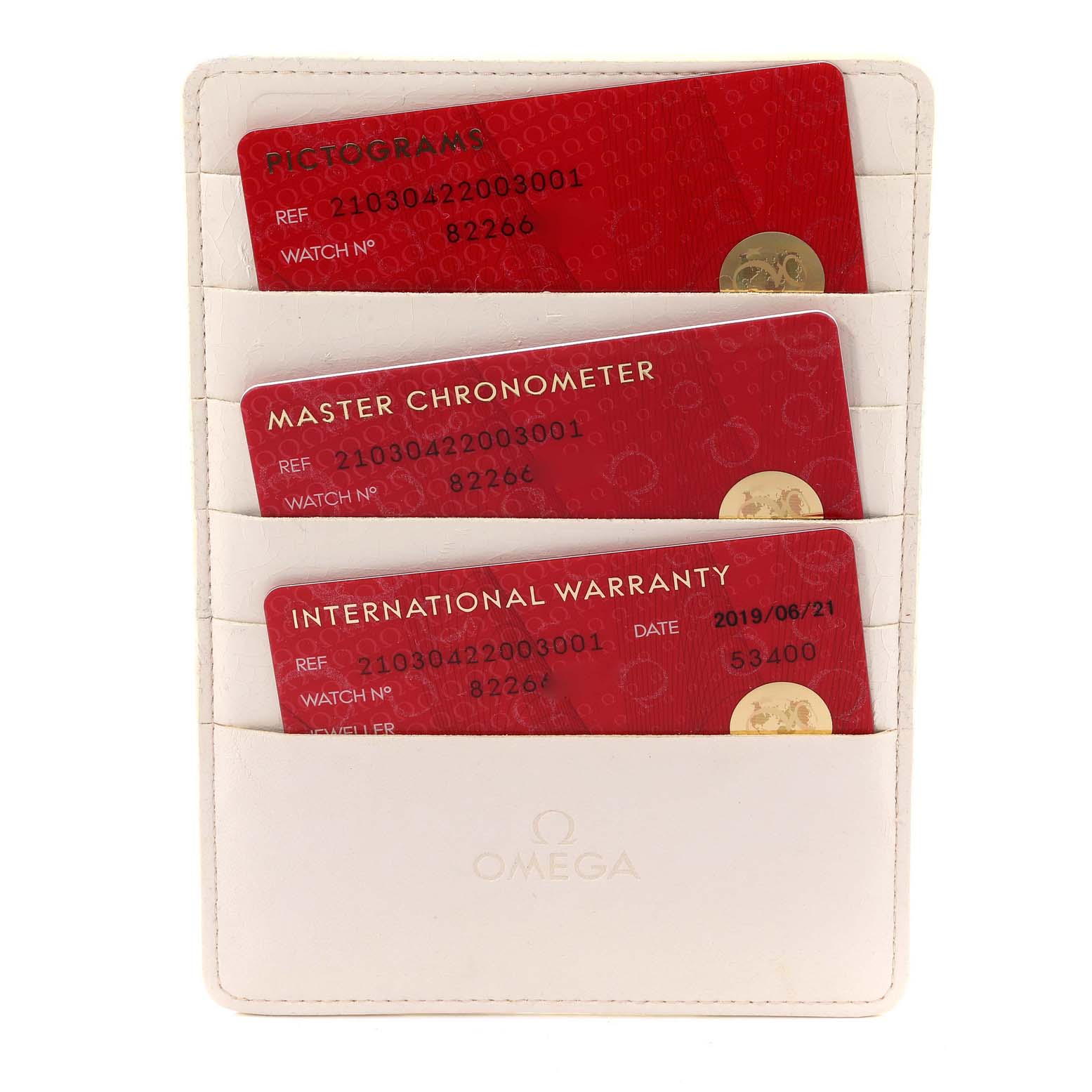 This image shows three red cards marked “Pictograms,” “Master Chronometer,” and “International Warranty” in a white Omega cardholder.