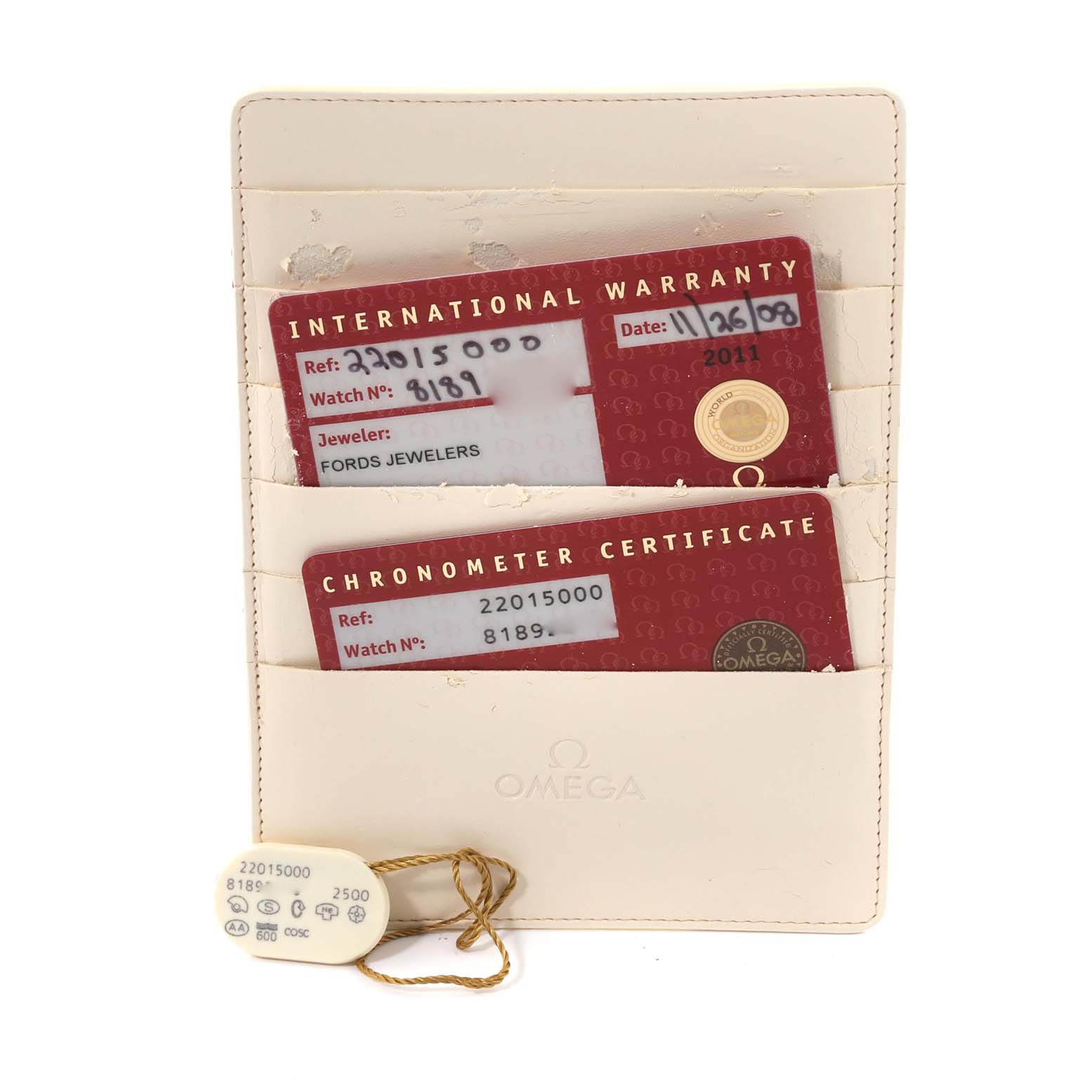 The image shows an Omega Planet Ocean 2201.50.00 Men
s Stainless Steel Black Dial 2201.50.00 Men
s Stainless Steel Black Dial watch
s international warranty card, chronometer certificate, and a tag, all neatly placed in a beige cardholder.