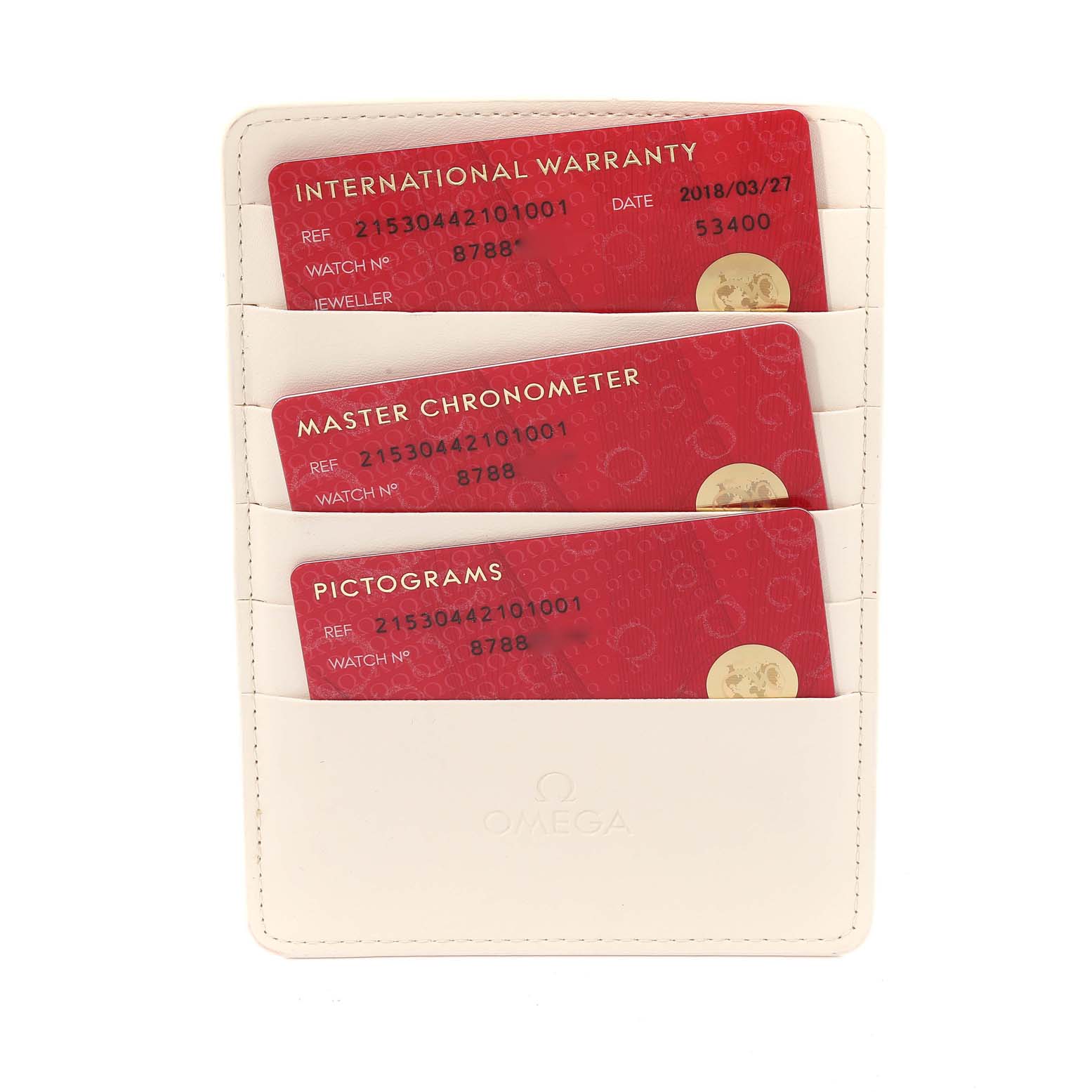 The image shows three red cards: International Warranty, Master Chronometer, and Pictograms, in a white Omega holder for a Planet Ocean model.