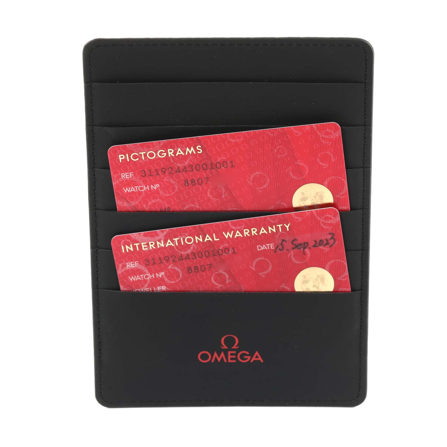 The image shows a black Omega cardholder with pictograms and international warranty cards for the Speedmaster model.