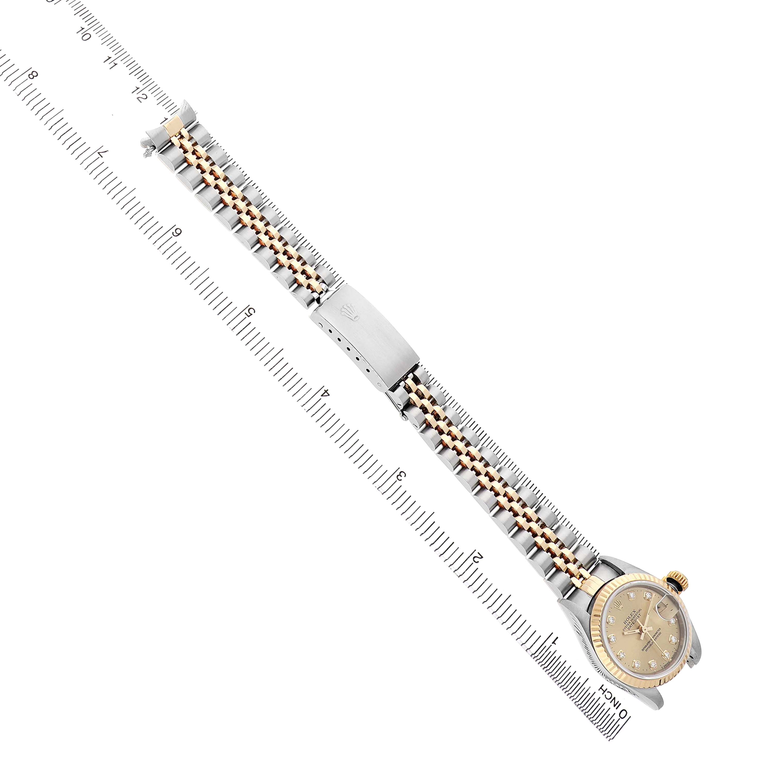 The Rolex Datejust 69173 Women's Steel and Gold (two tone) Champagne Dial watch is displayed at an angle, showing the full bracelet, clasp, and dial alongside a ruler for scale.