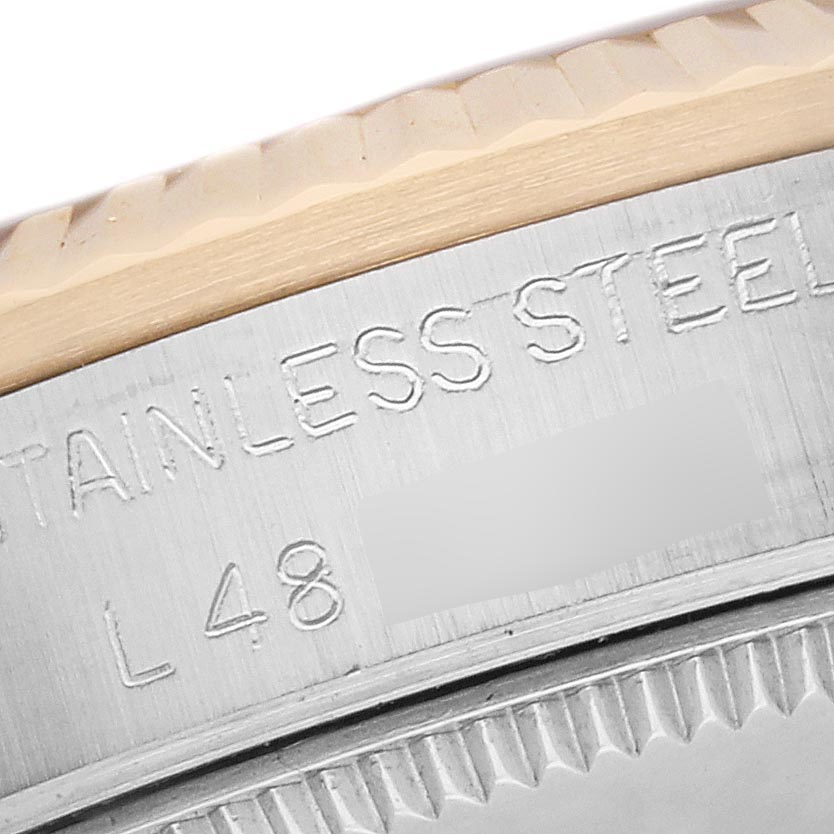 This image shows a close-up of the case and bezel of a Rolex Mid-Size 68273 Women's Steel and Gold (two tone) Champagne Dial 68273 Women's Steel and Gold (two tone) Champagne Dial watch, highlighting the "STAINLESS STEEL" engraving.